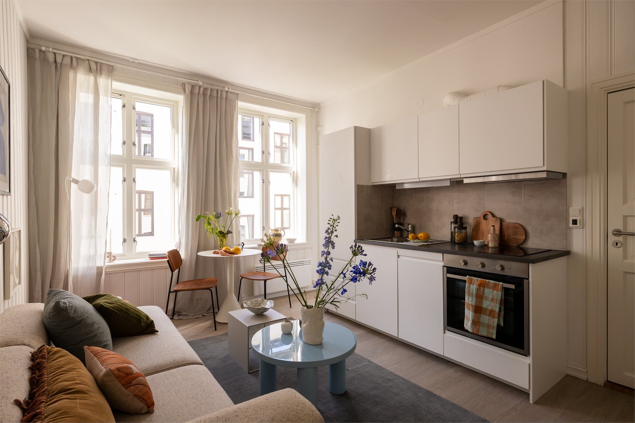 Et lyst og delikat kjøkken med integrerte hvitevarer som stekeovn, platetopp, kjøl-/fryseskap og oppvaskmaskin (smal type).