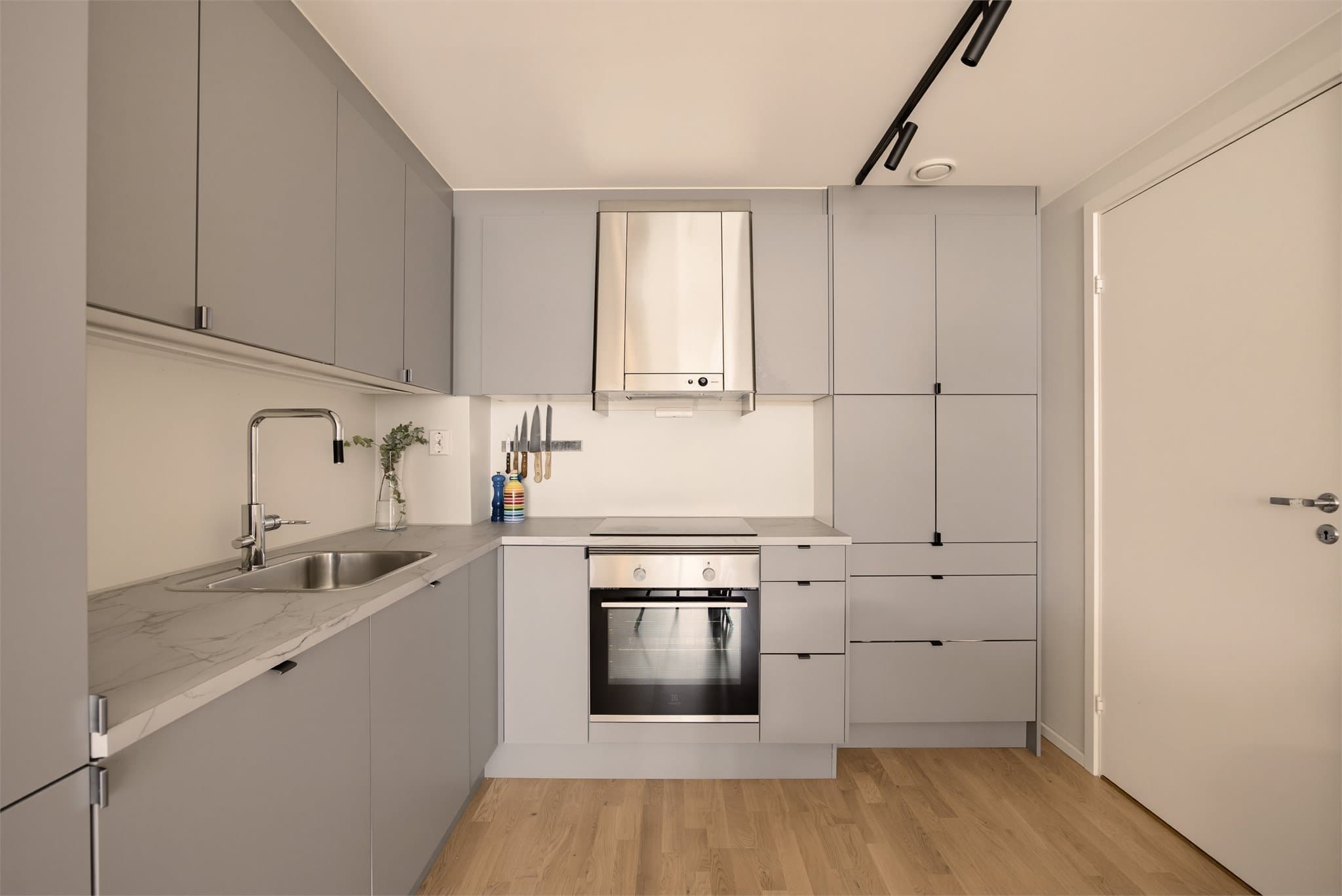 Kjøkkenet har innredning fra HTH med slette, grå fronter og laminat benkeplate. Kjøkkeninnredningen er utvidet med takhøyt oppbevaringsskap.