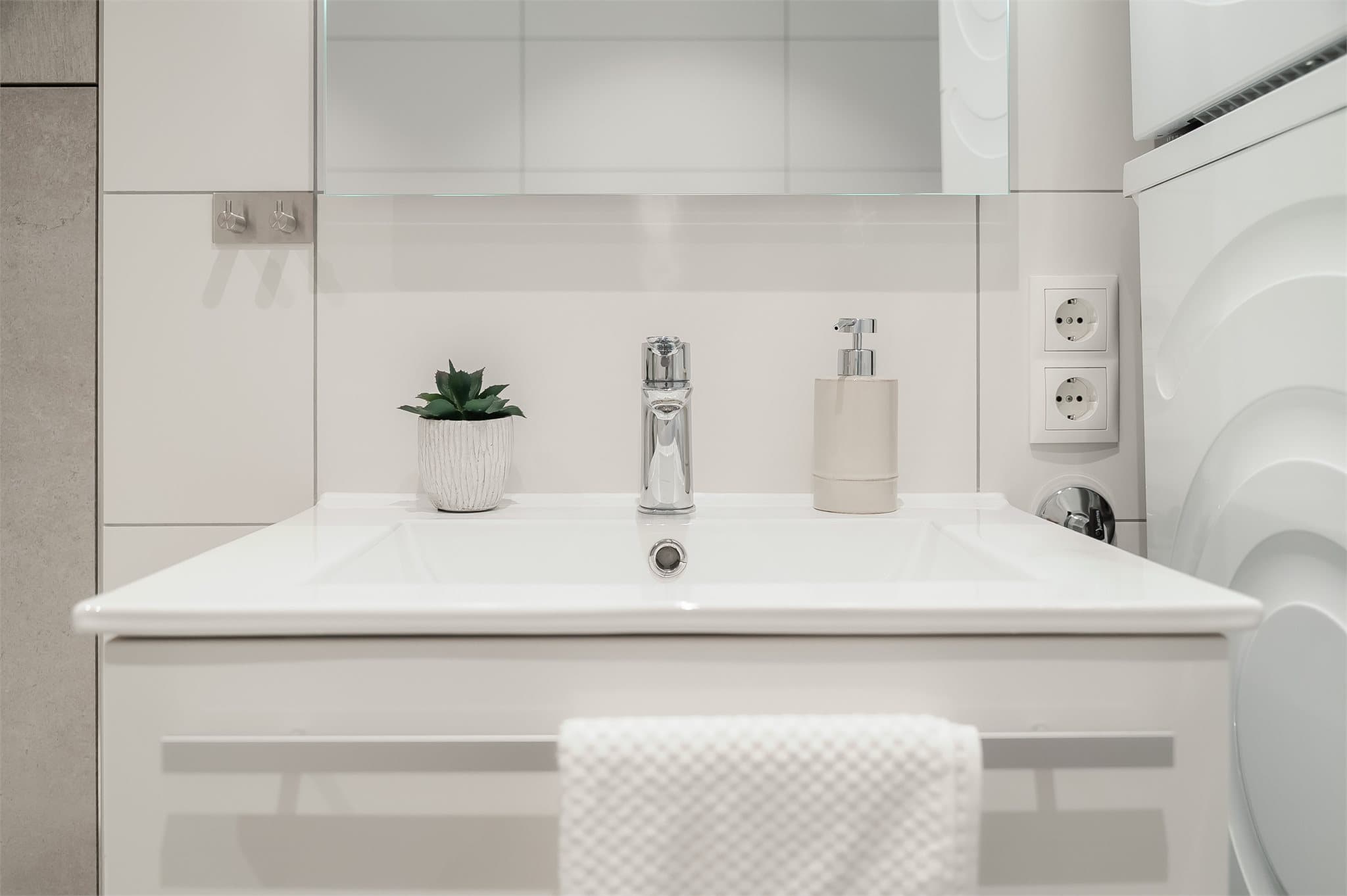 Stilren servantinnredning med gode oppbevaringsmuligheter samt speil med integrert belysning.