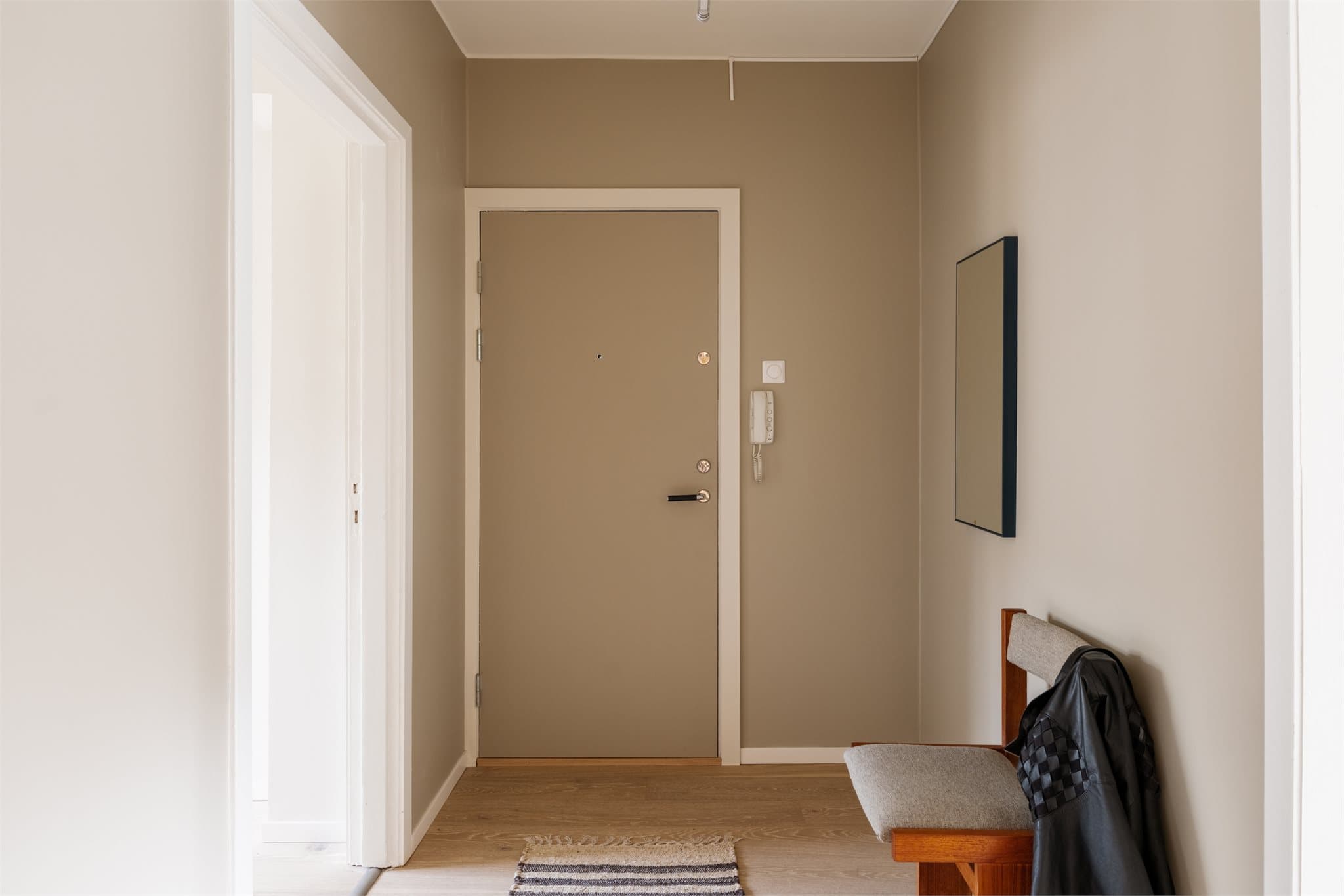 Entréen fremstår ryddig og funksjonell med beige vegger, hvite detaljer og lyst tregulv.