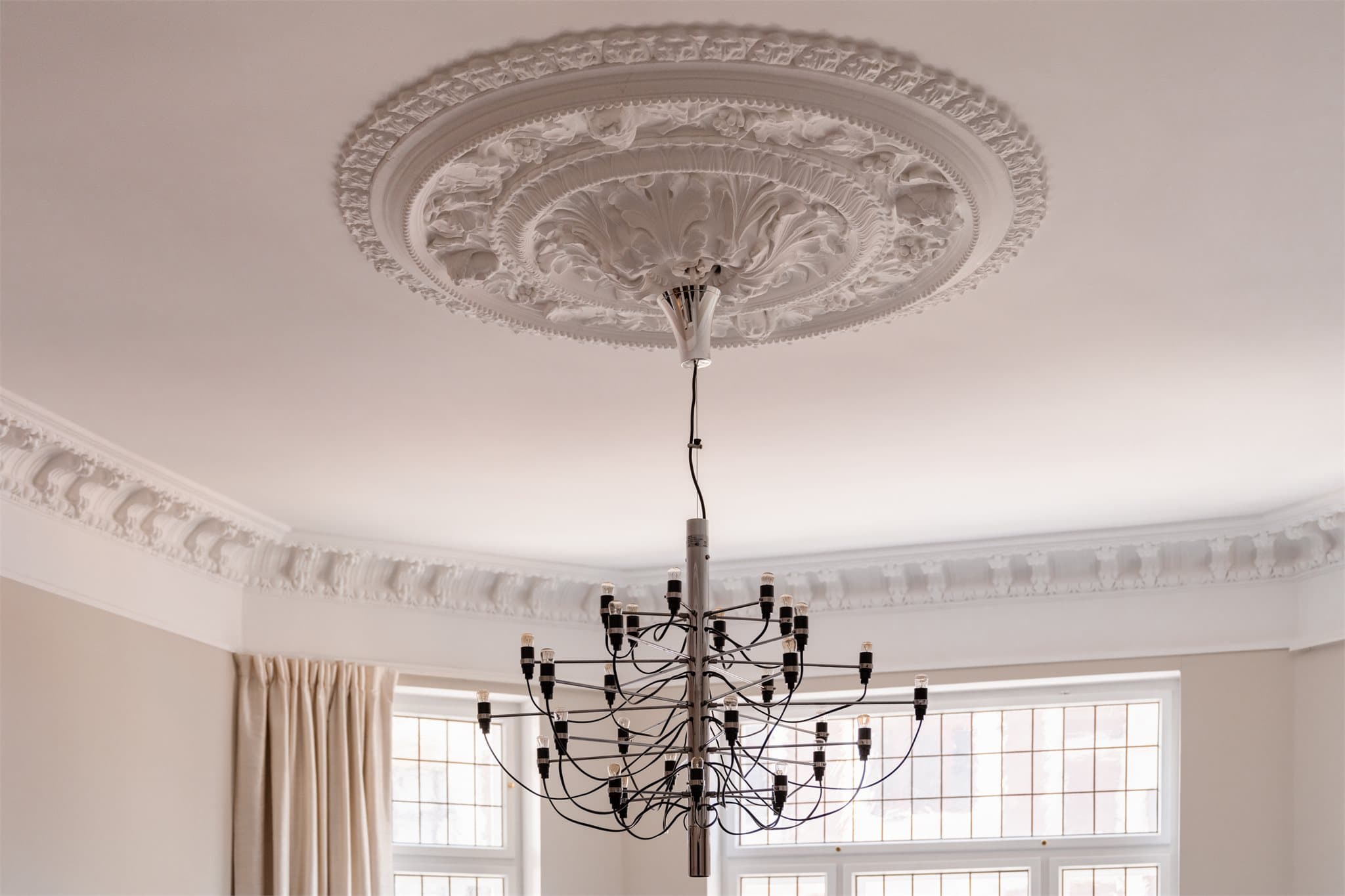 Originale detaljer som stukkatur og rosetter i taket understreker leilighetens historiske sjarm.