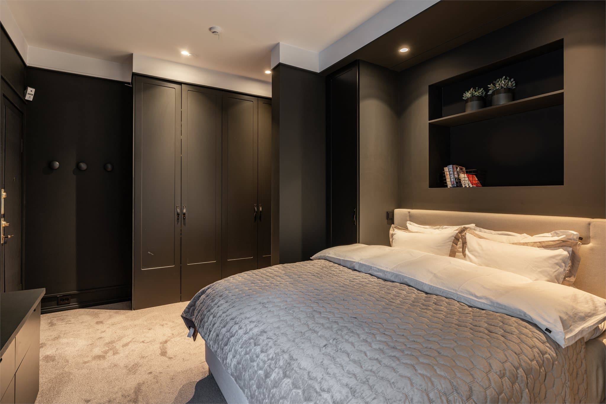 Rommet har gjennomførte, plassbygde garderobeløsninger som også er integrert rundt dobbeltsengen, samt en nisjeløsning i vegg. Under vinduet er det etablert en plassbygget sjenk som både er praktisk og estetisk tiltalende.