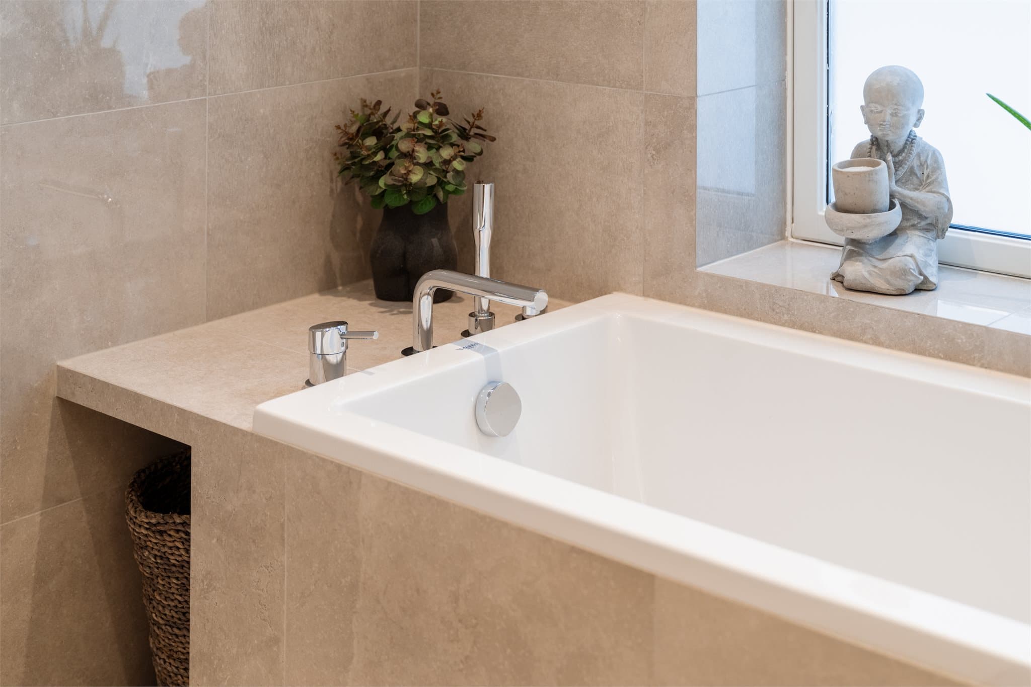 Hovedbadet er svært smakfullt med et innfliset badekar som understreker rommets helhetlige og eksklusive preg.