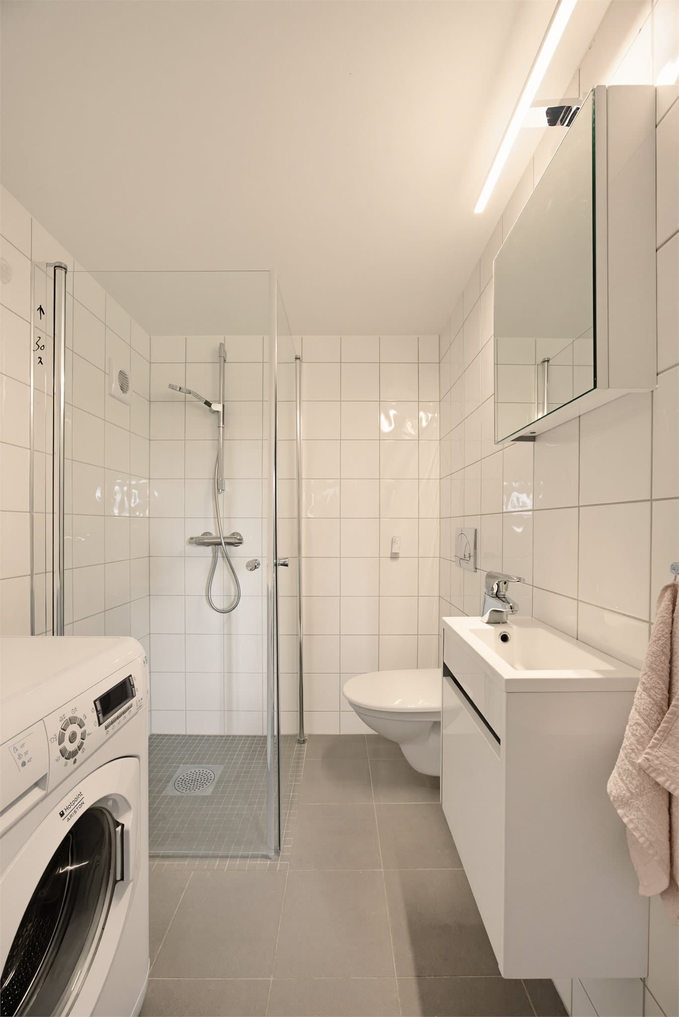 Badet i underetasjen er innredet med skap med glatte fronter, servant, klosett og dusj på gulv. Opplegg for vaskemaskin.