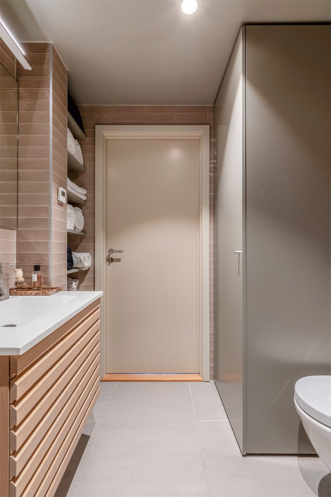 Rommet er helfliset og har et tidløst uttrykk som kombinerer funksjonalitet med estetikk. Vannbåren gulvvarme sørger for en behagelig og lun atmosfære, og understreker badets helhetlige kvalitetsfølelse.