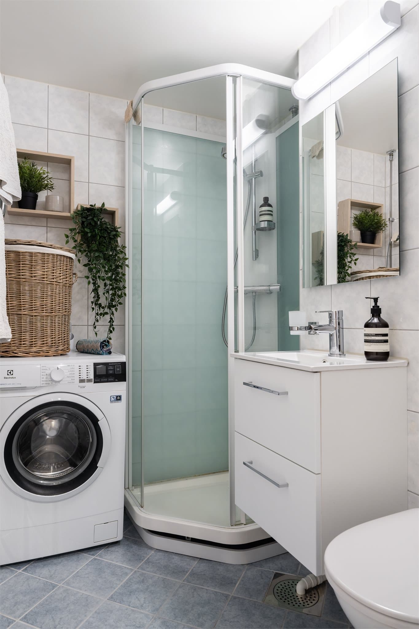 Badet har elektrisk gulvvarme, dusjkabinett, vegghengt toalett og servant med praktisk innredning.