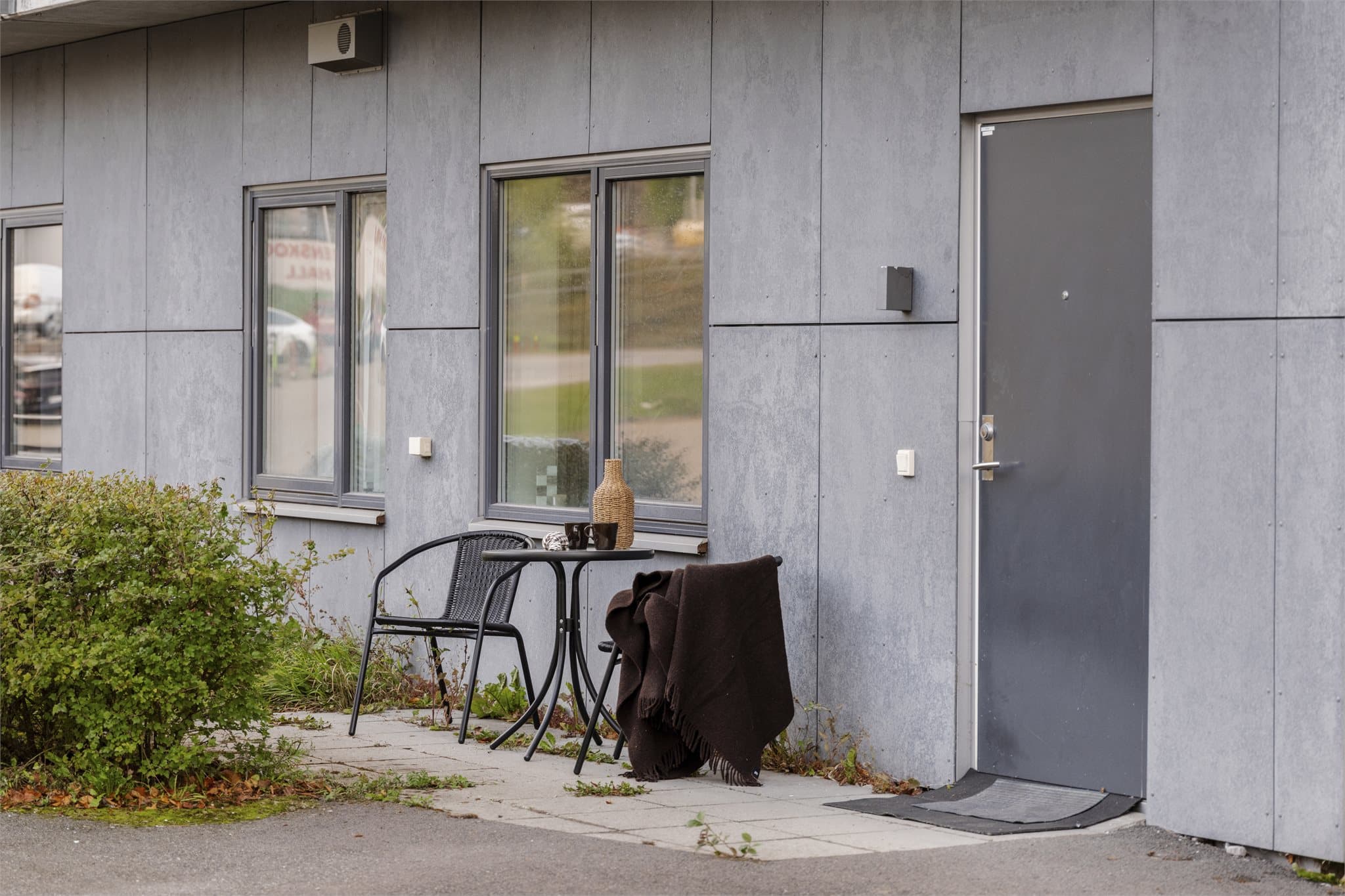 Inngangsparti på bakkeplan med hellelagt uteplass ved døren.