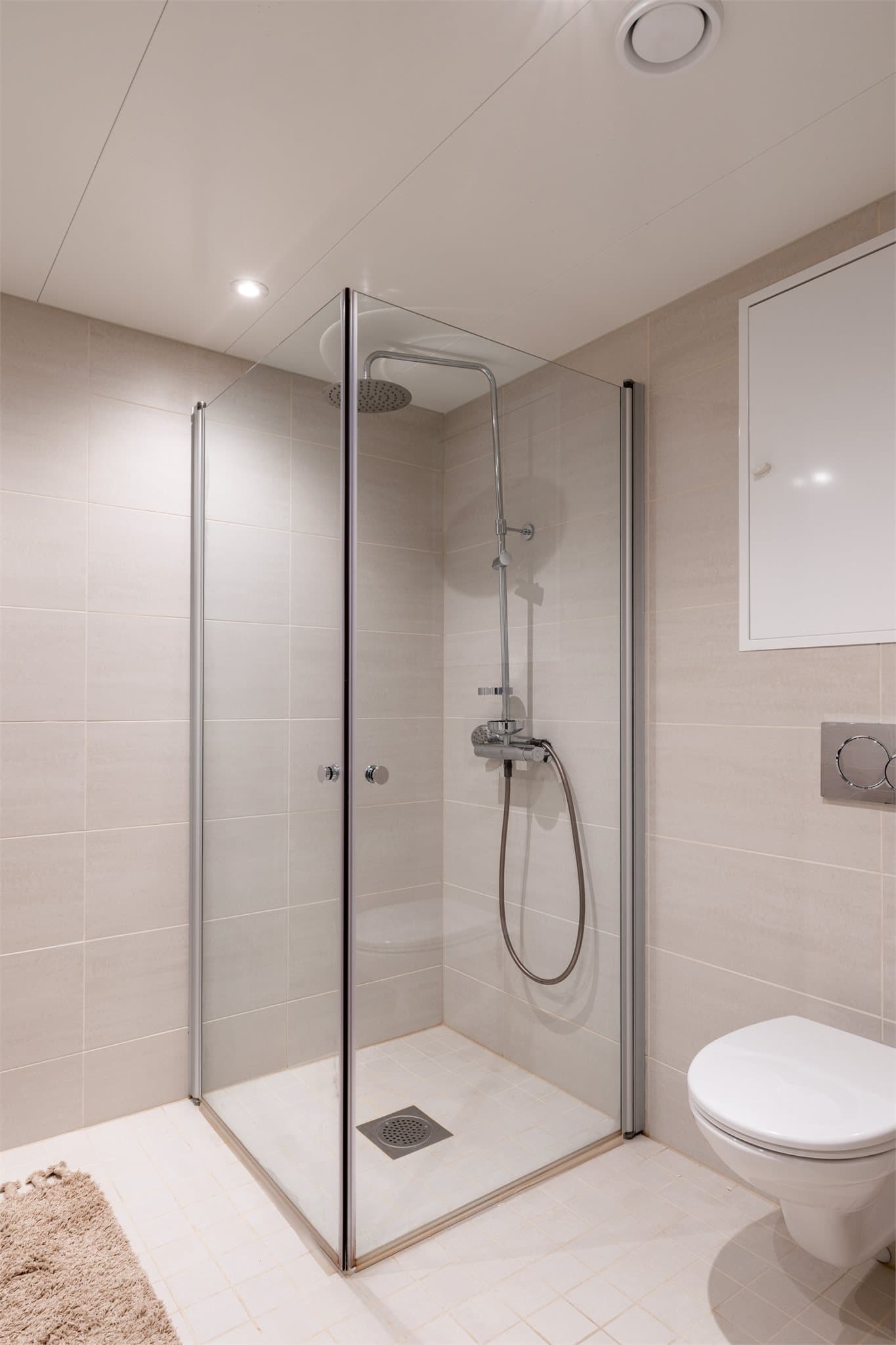 Videre er det en romslig dusjnisje bak innfellbare dusjdører, samt vegghengt toalett.