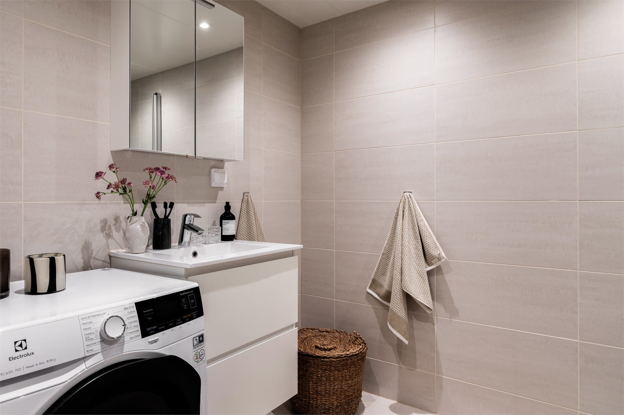 Badet har stilren baderomsinnredning med underskuffer og opplegg for vaskemaskin.