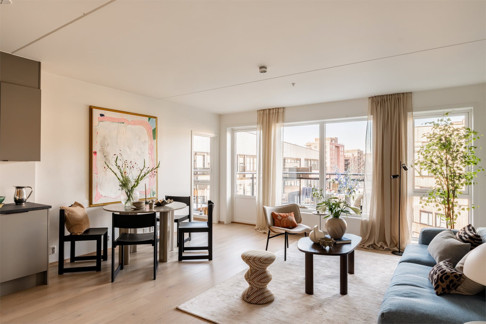 Oppholdsrommet fremstår lyst, moderne og innbydende med store vindusflater som slipper inn rikelig med dagslys.