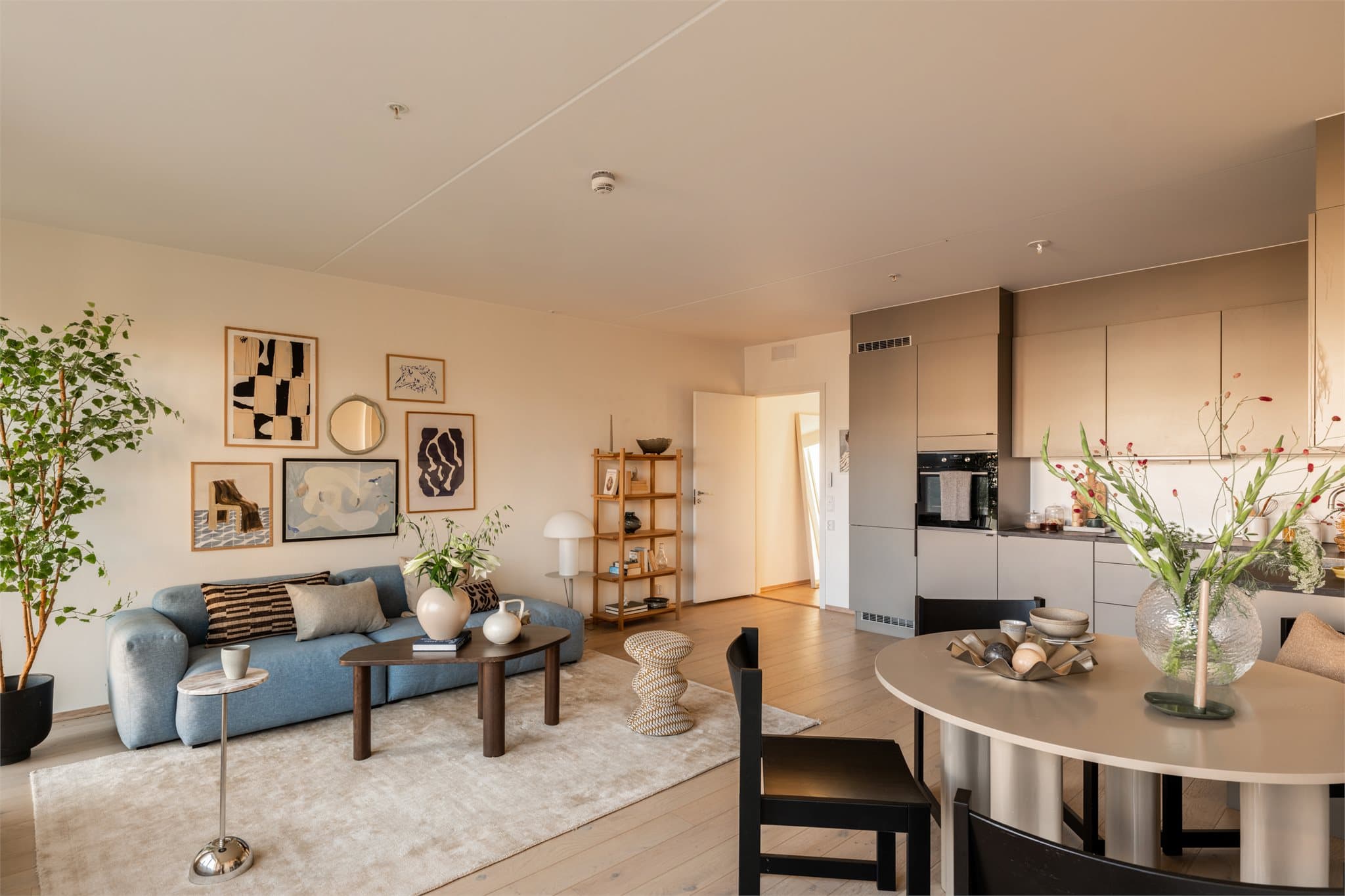 Den åpne løsningen mellom kjøkken og stue gir en naturlig soneinndeling, hvor kjøkkenet har en stilren innredning med gode oppbevarings- og arbeidsflater.