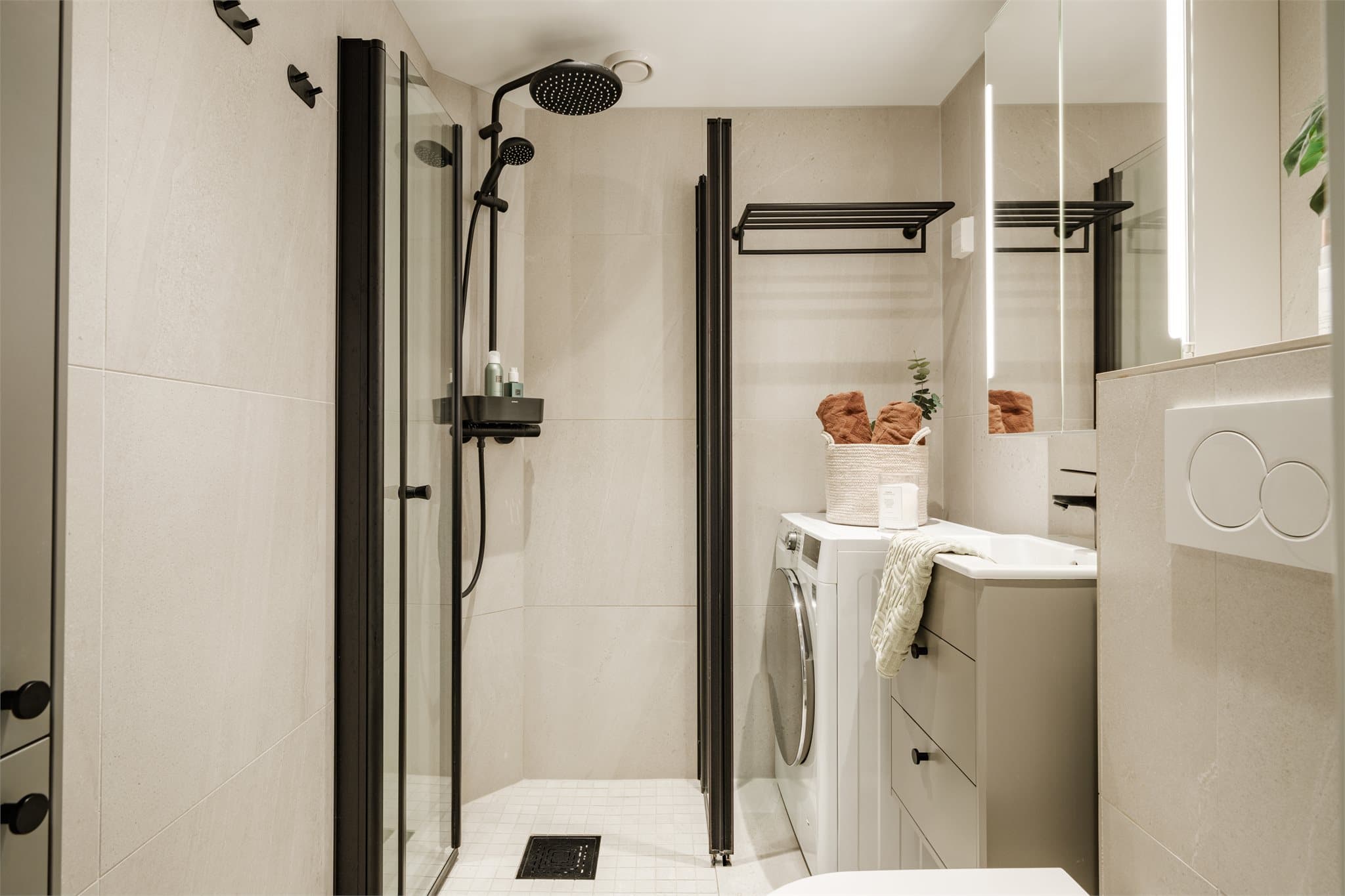 Lekkert flislagt bad med opplegg for vaskemaskin.