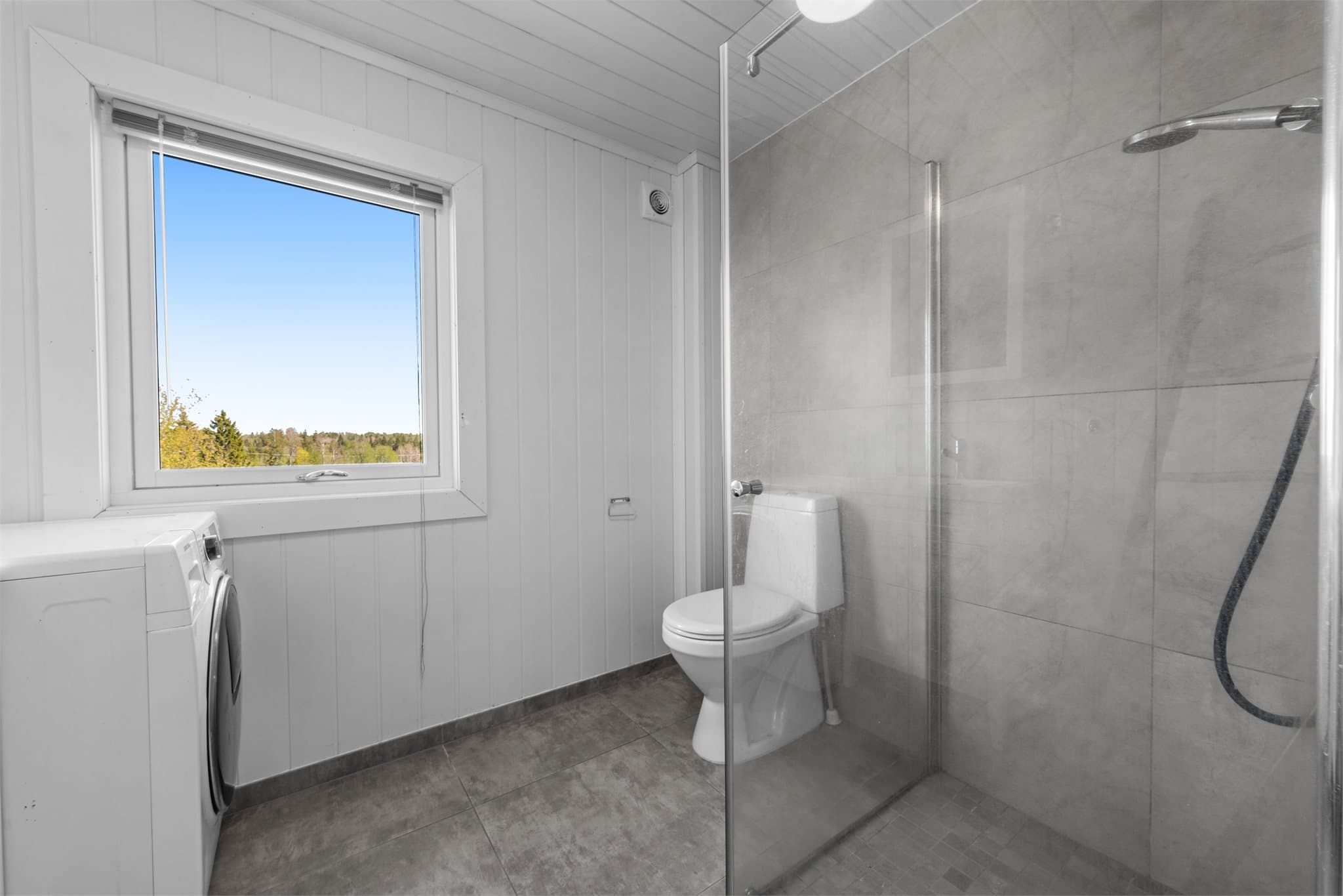 Bad kårbolig med dusløsning, toalett, servant og opplegg for oppvaskmaskin.