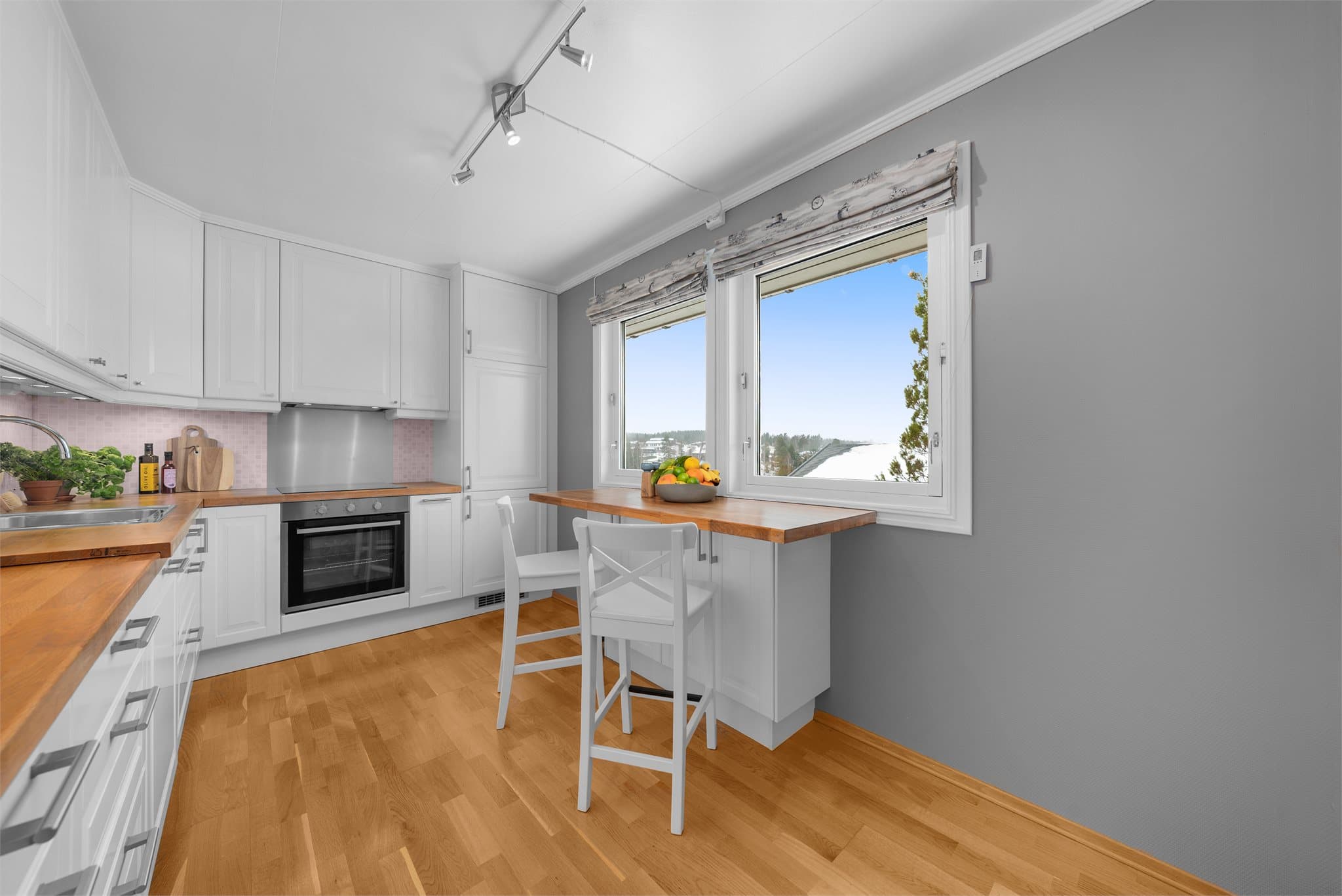 Kjøkkenet har en pen, klassisk kjøkkeninnredning med takhøye skap.