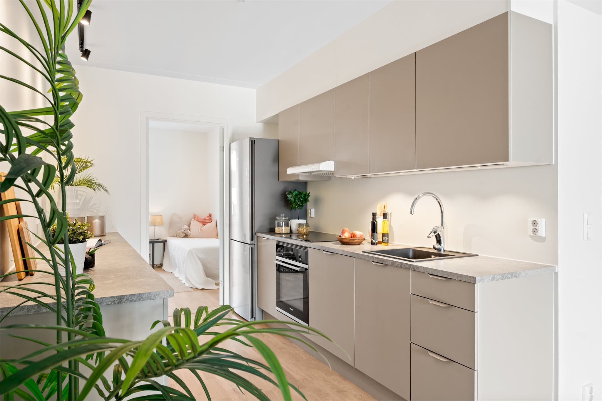 Kjøkkenet er utstyrt med glatte skapfronter i en elegant og nøytral fargetone, kombinert med laminat benkeplater som gir god arbeidsflate og et helhetlig utrykk.