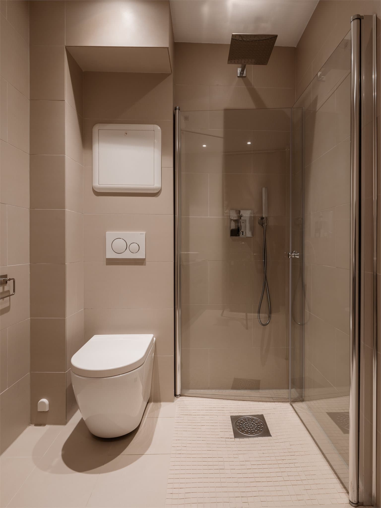 Dusjhjørne med svingbare glassdører og vegghengt toalett.