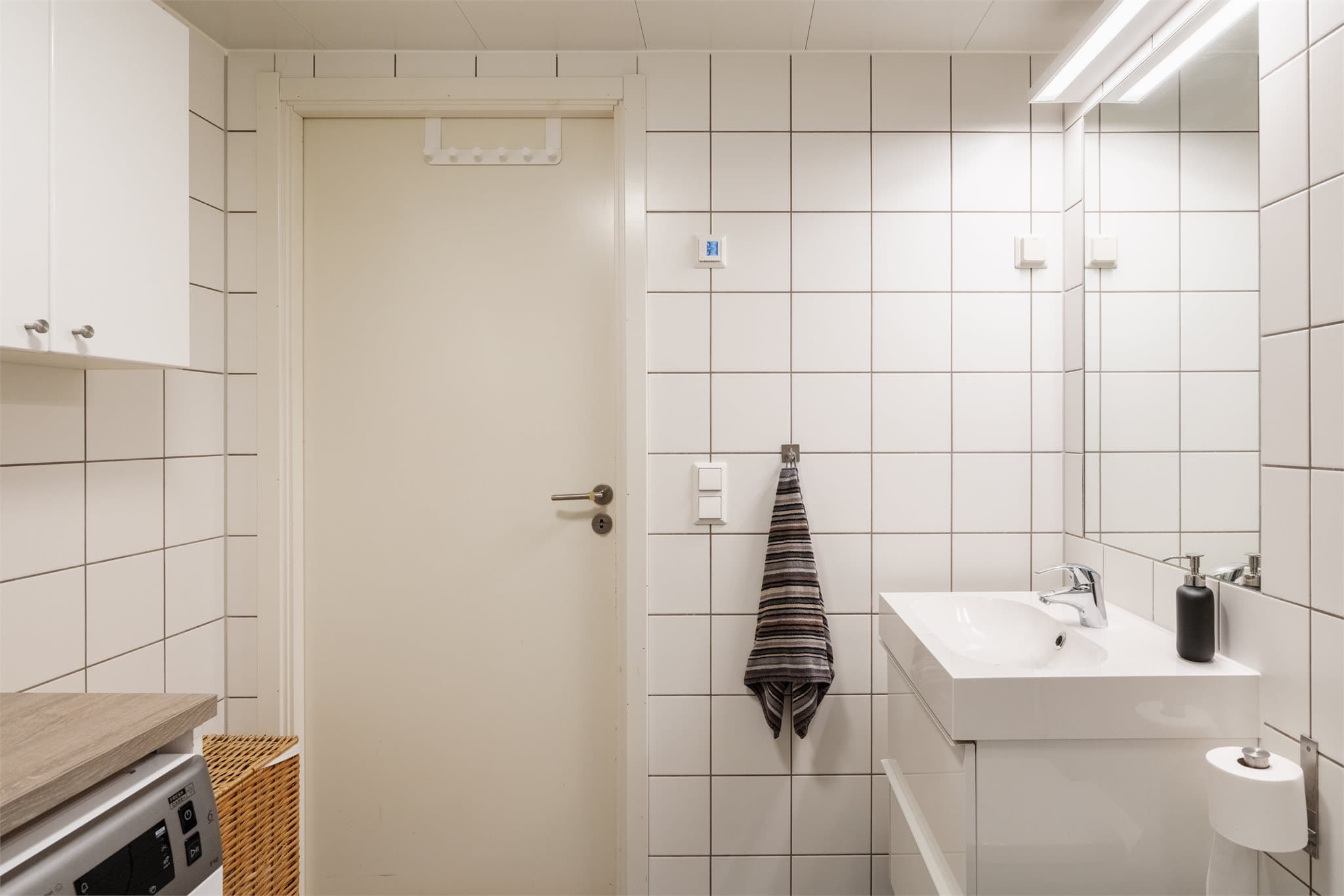 Baderomsinnredning med heldekkende servant og speil med belysning.