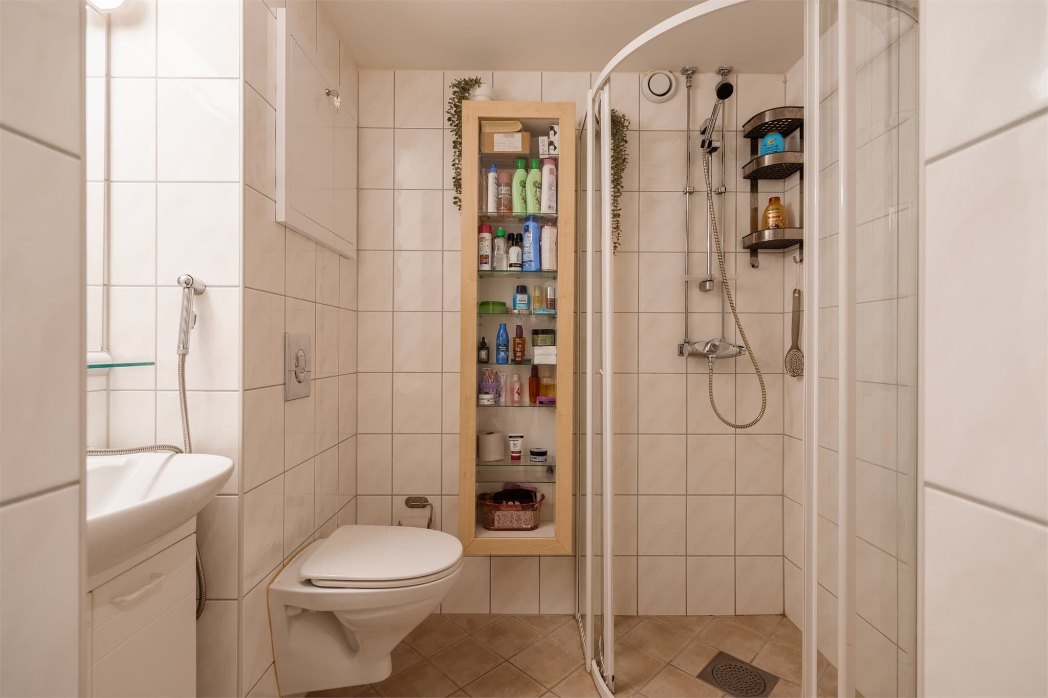 Delikat flislagt baderom med vegghengt toalett.