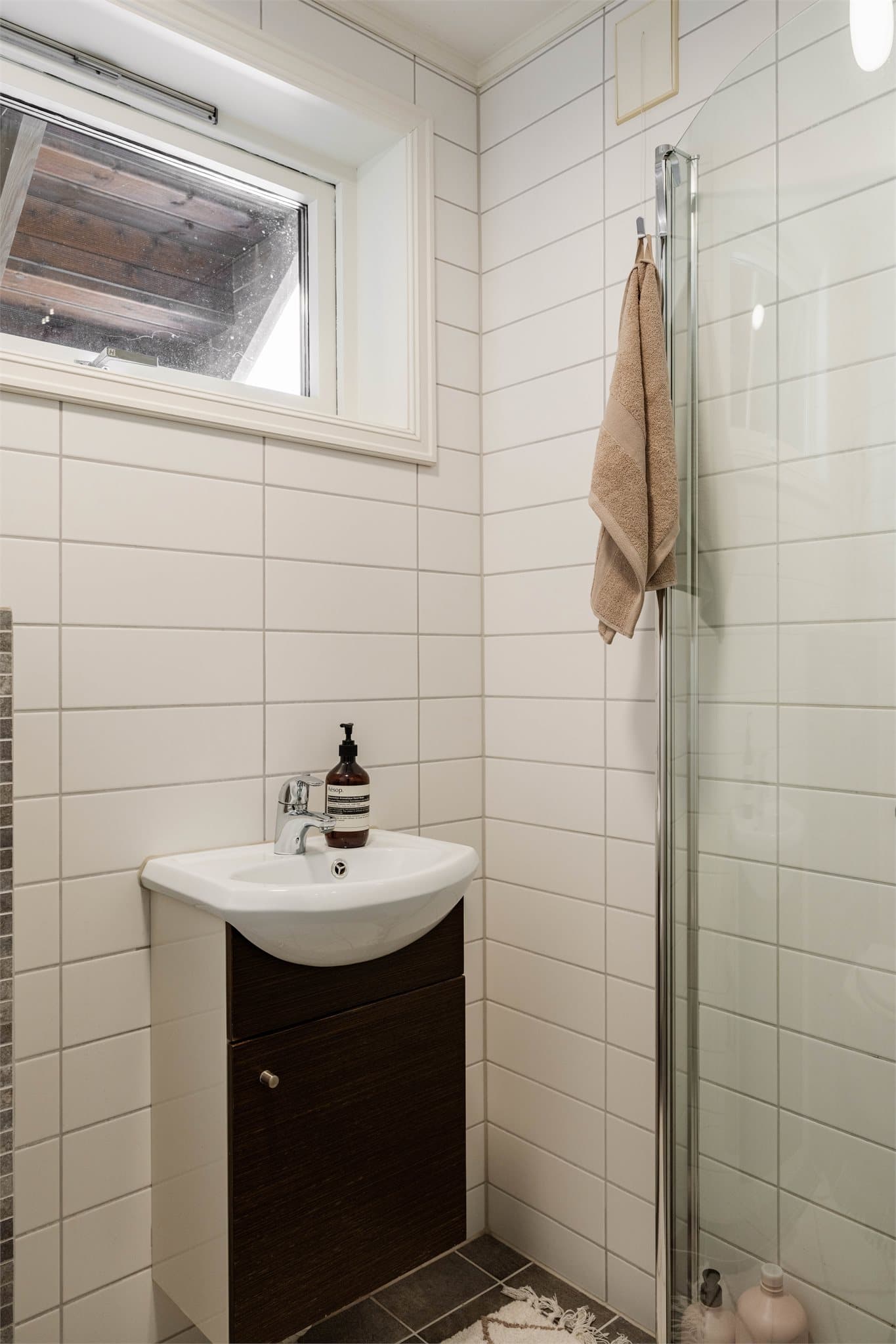 Badet er utstyrt med dusjhjørne med svingbare glassdører.
