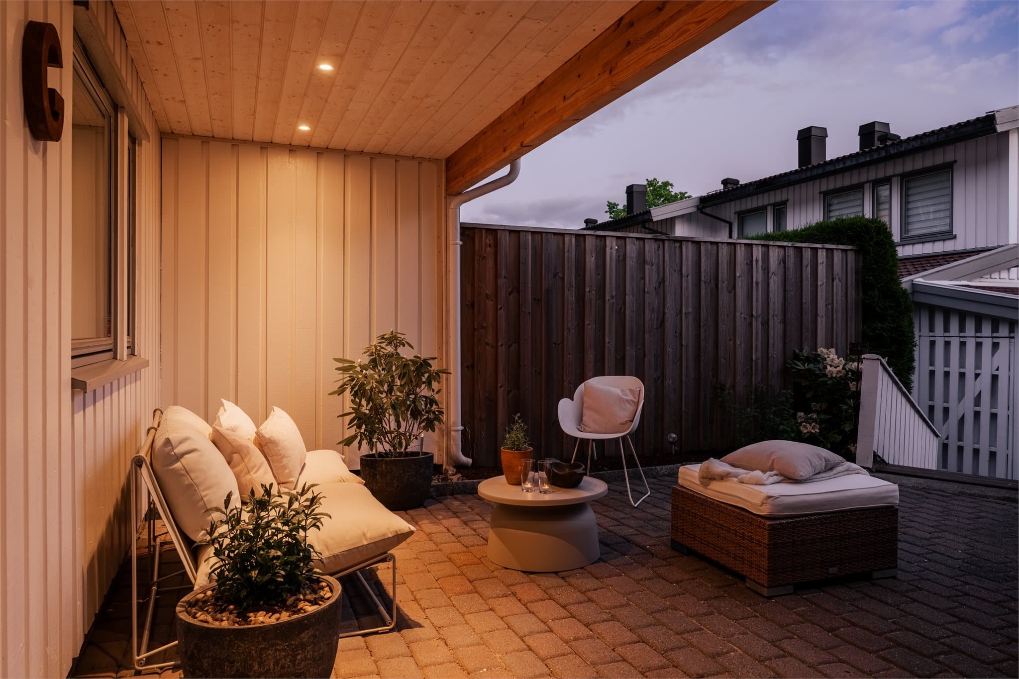 Brosteinsdekke og beplantningsmuligheter skaper en innbydende og privat forhage med plass til bl.a. sittegruppe.