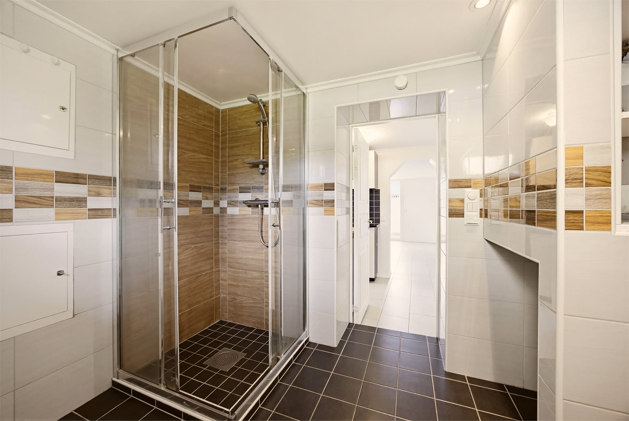 Badet er utstyrt med vegghengt toalett, bidet, dusj med skyvbare glassdører og har opplegg for vaskemaskin.
