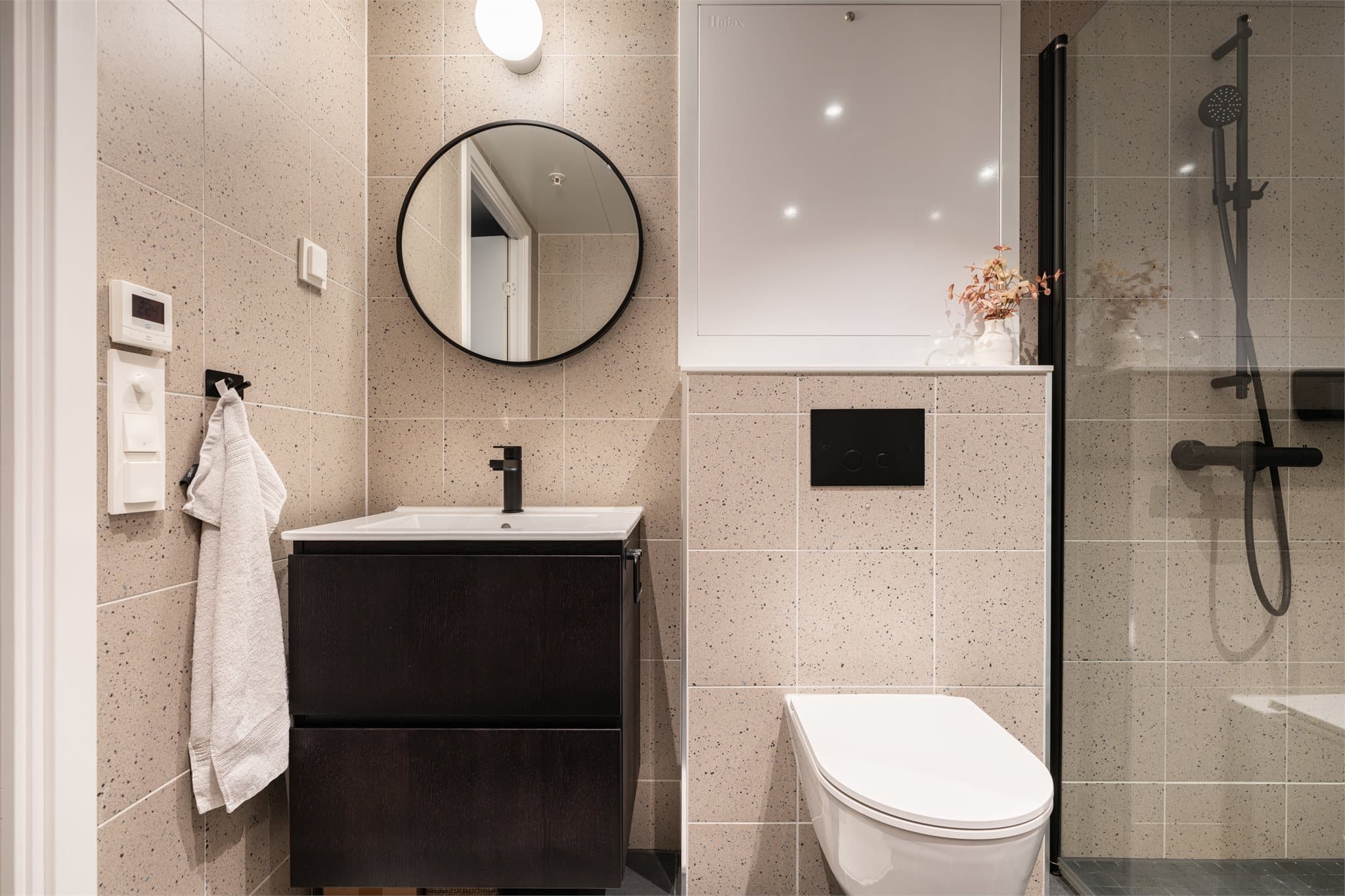 Badet har vegghengt toalett og servant med underskap.