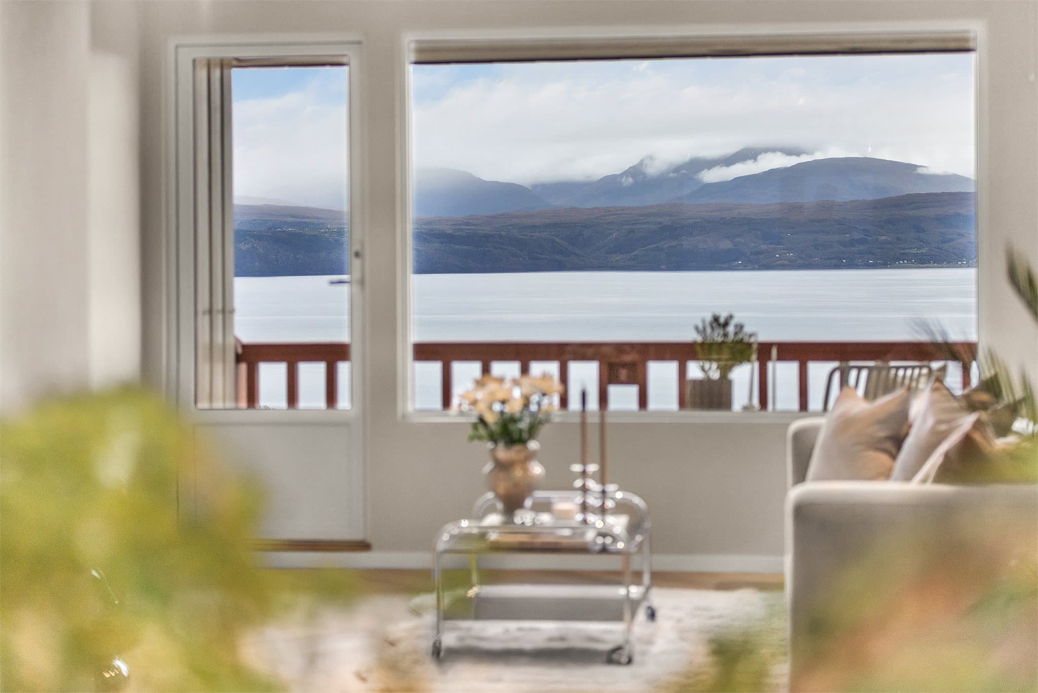 Vindusposten rammer inn det åpne fjord- og fjellandskapet.