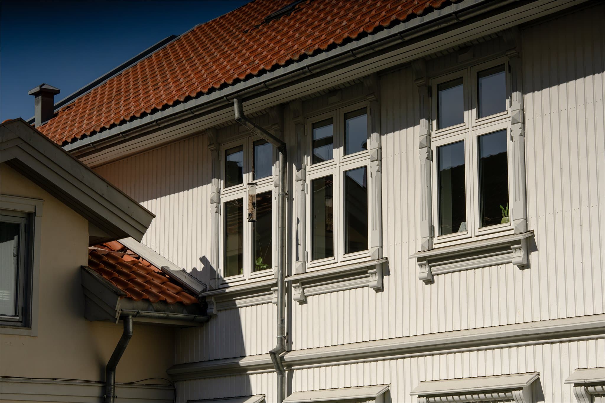 Bygningen har stående bordkledning, teglsteinsdekket tak og sinkbeslag.