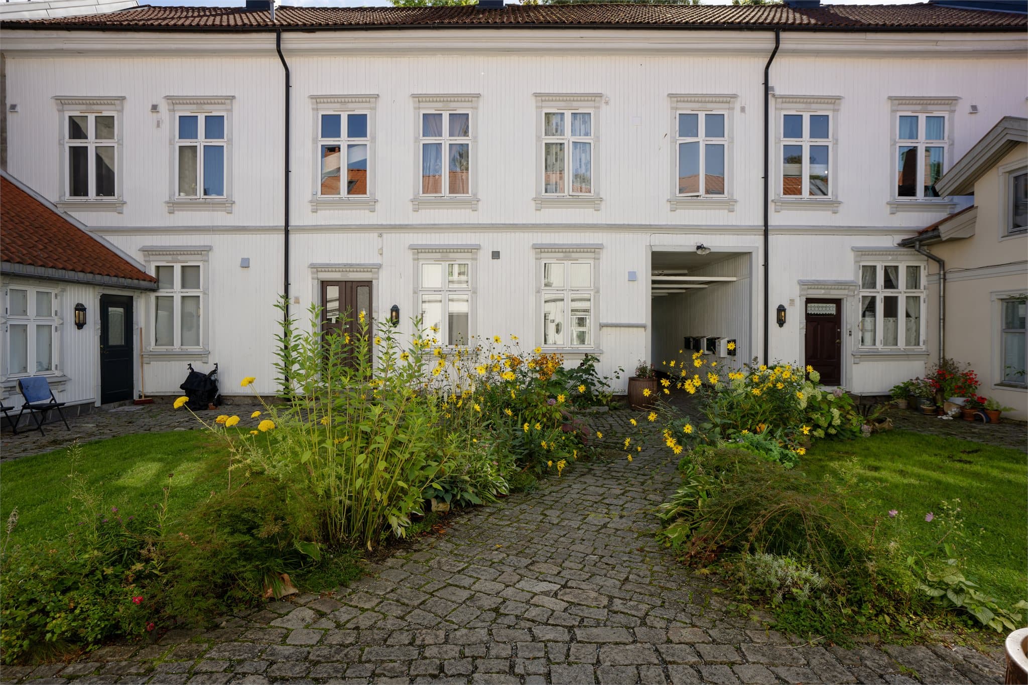 Felles bakgård omkranset av velholdt trehusbebyggelse og blomsterbed.
