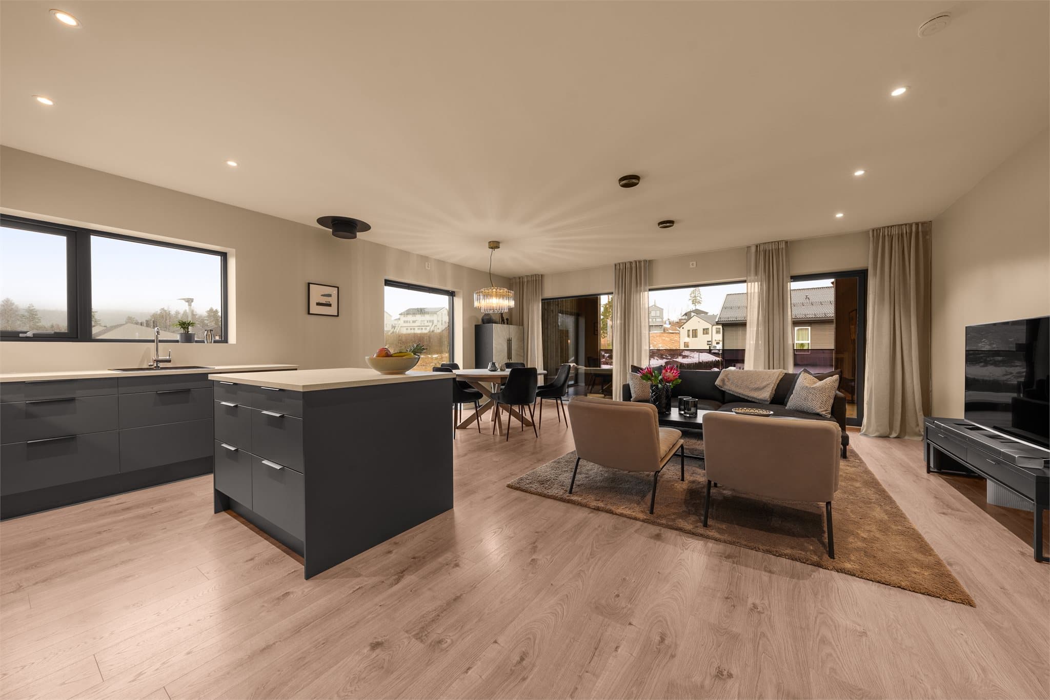 Stor stue med moderne og fine fargevalg. Downlights i himling og store vindusflater mot syd (langsiden) gir gode naturlige lysforhold