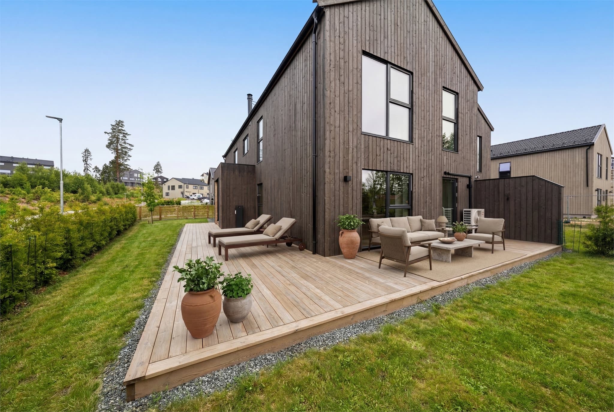 Store uteområder og stor terrasse. Hagen er pent skjermet inn med Thuja og gjerde. Gode solforhold i sydvendt del av hagen. Bildet er digitalt møblert og redigert og avvik kan dermed forekomme