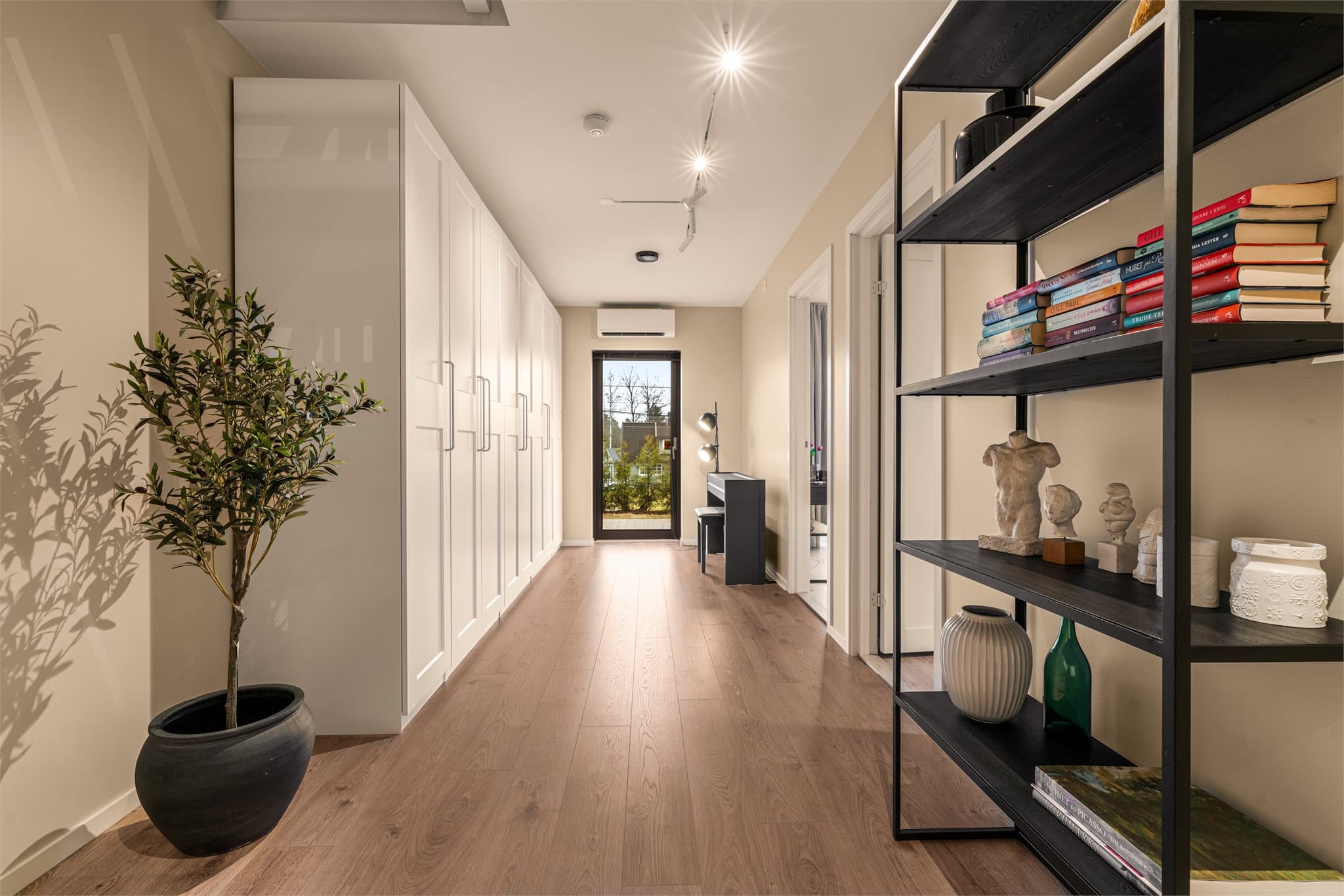 Tv-stue i 1.etasje innredet med løse garderobeskap og utgang til terrassen