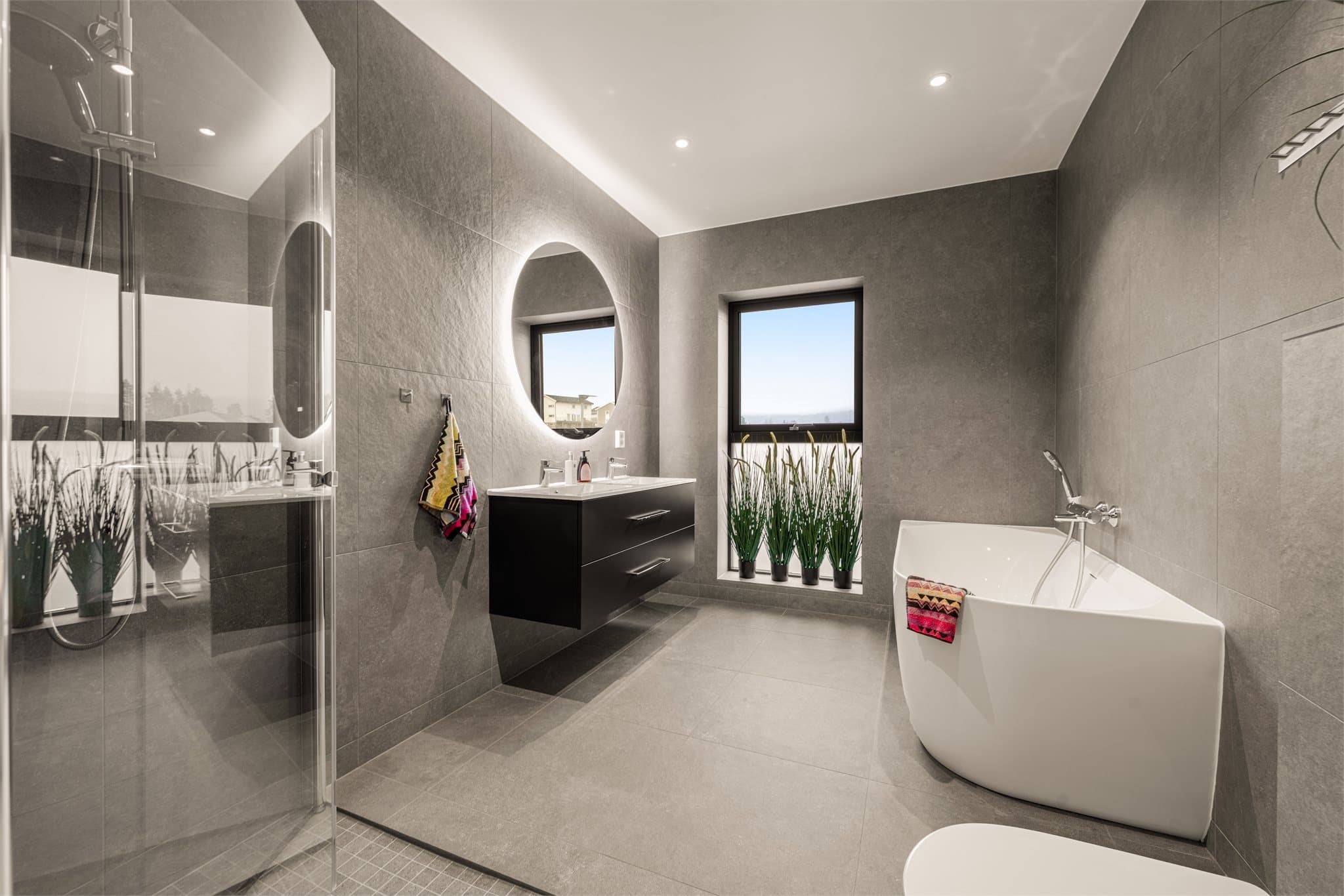 Flislagt og delikat baderom med både badekar og dusj