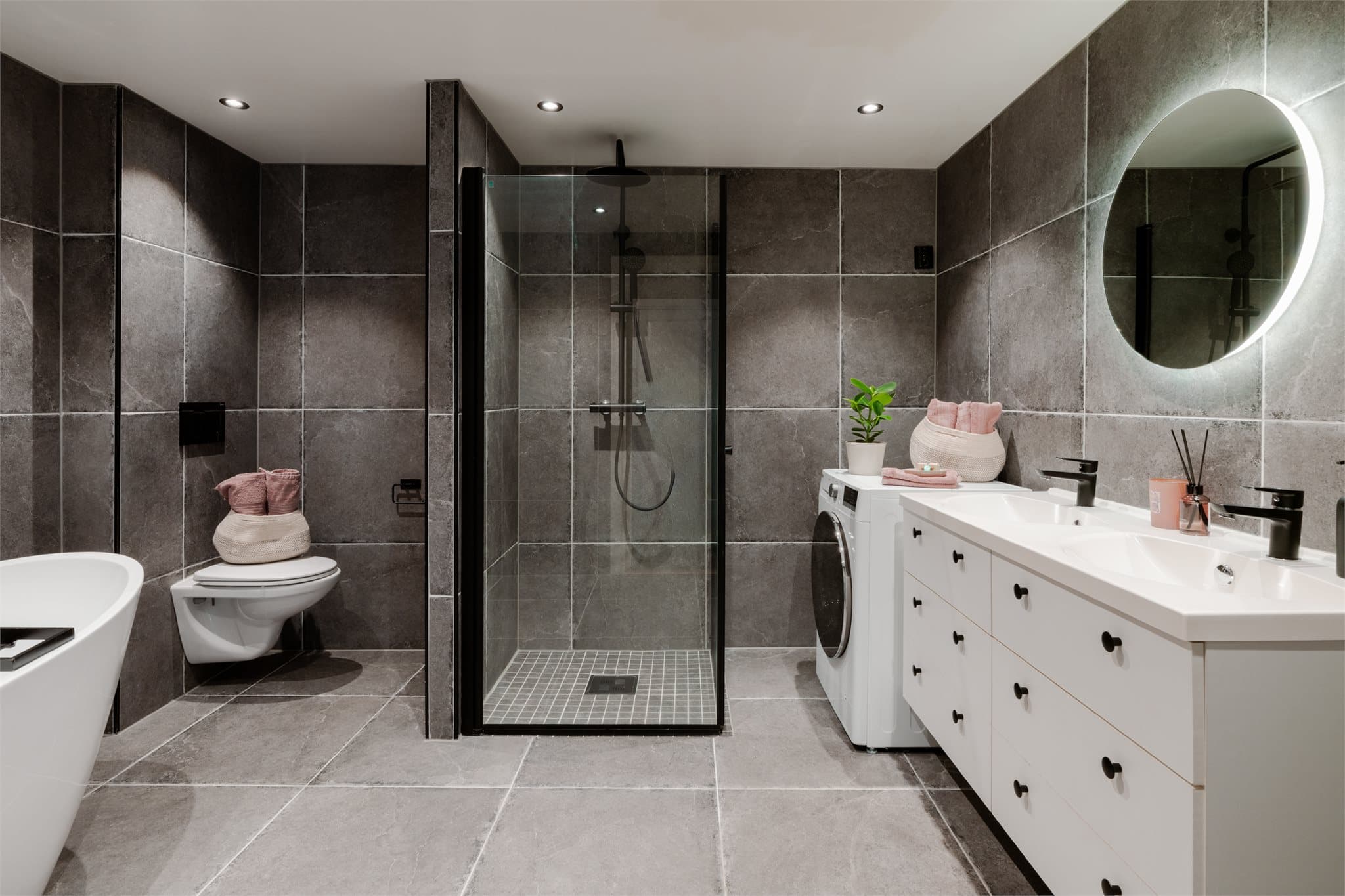 Leiligheten har et stort baderom med flislagte overflater og varme i gulvet.