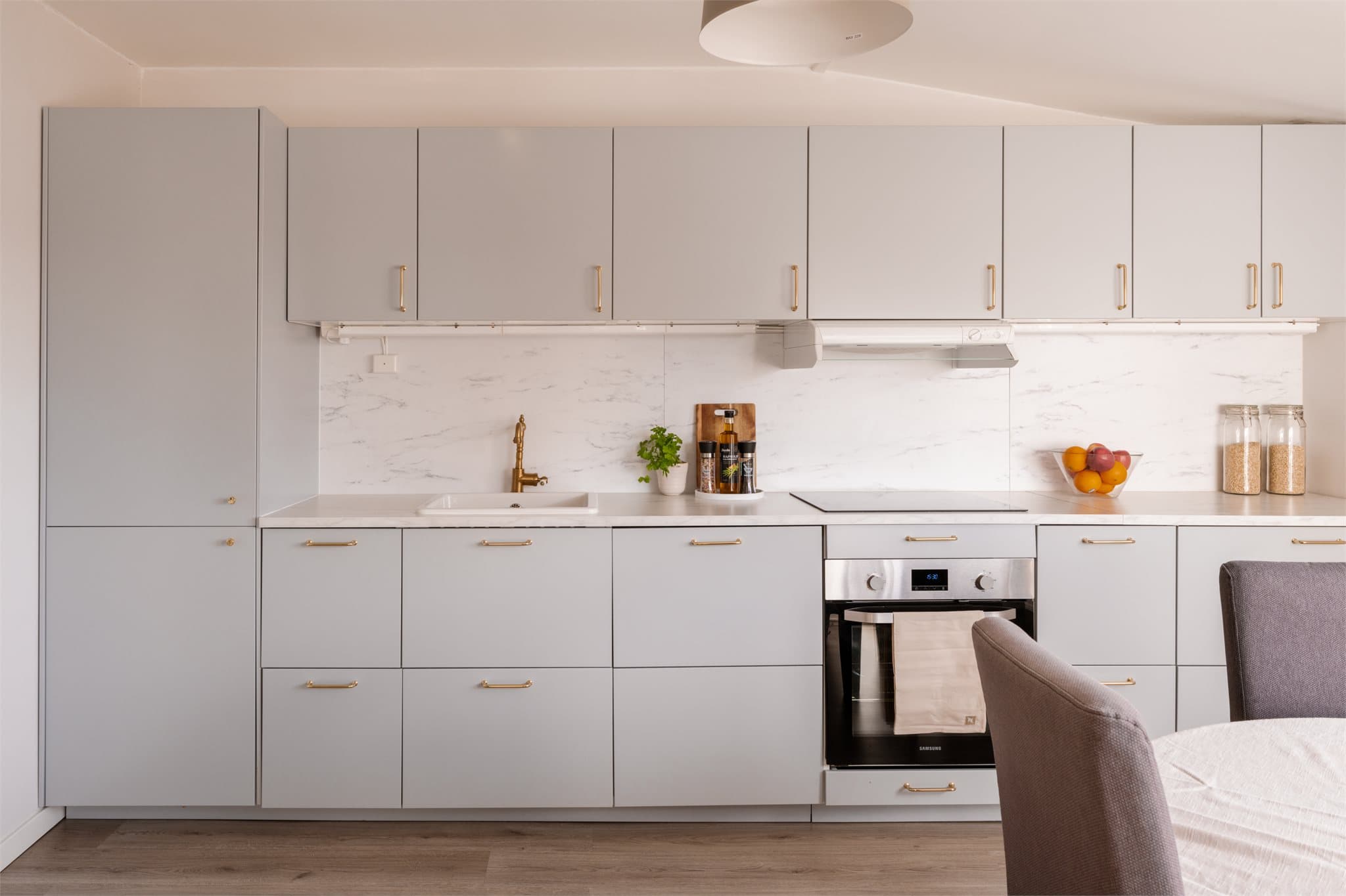 Et lyst og delikat kjøkken fra Ikea med glatte fronter og laminat benkeplate med nedfelt stålkum.