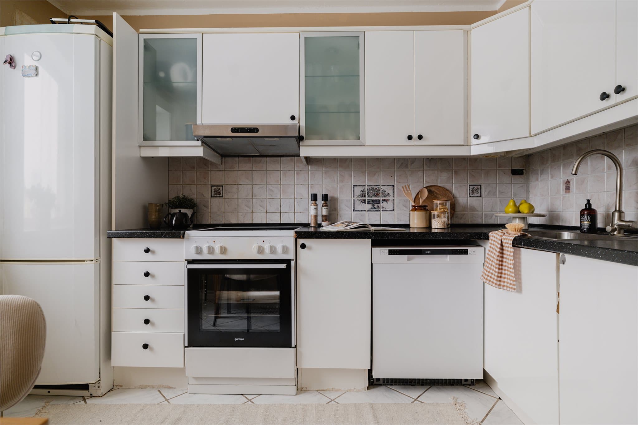 Kjøkkenet har en funksjonell innredning med glatte, folierte fronter og en benkeplate i laminat med nedfelt kum i rustfritt stål.