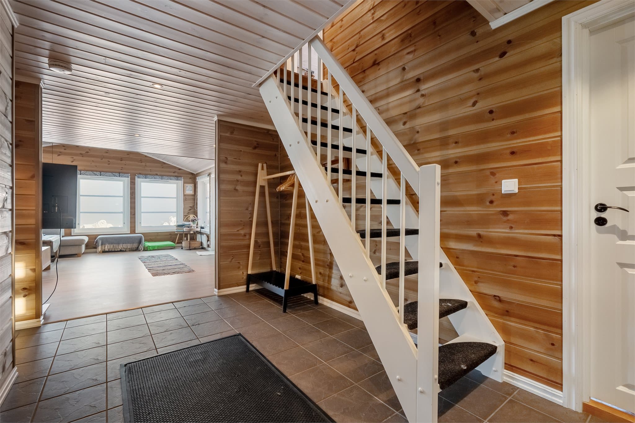 Velkommen inn! Romslig entré med fliser på gulv og panelkledde vegger. Det er godt med plass til klesoppbevaring.