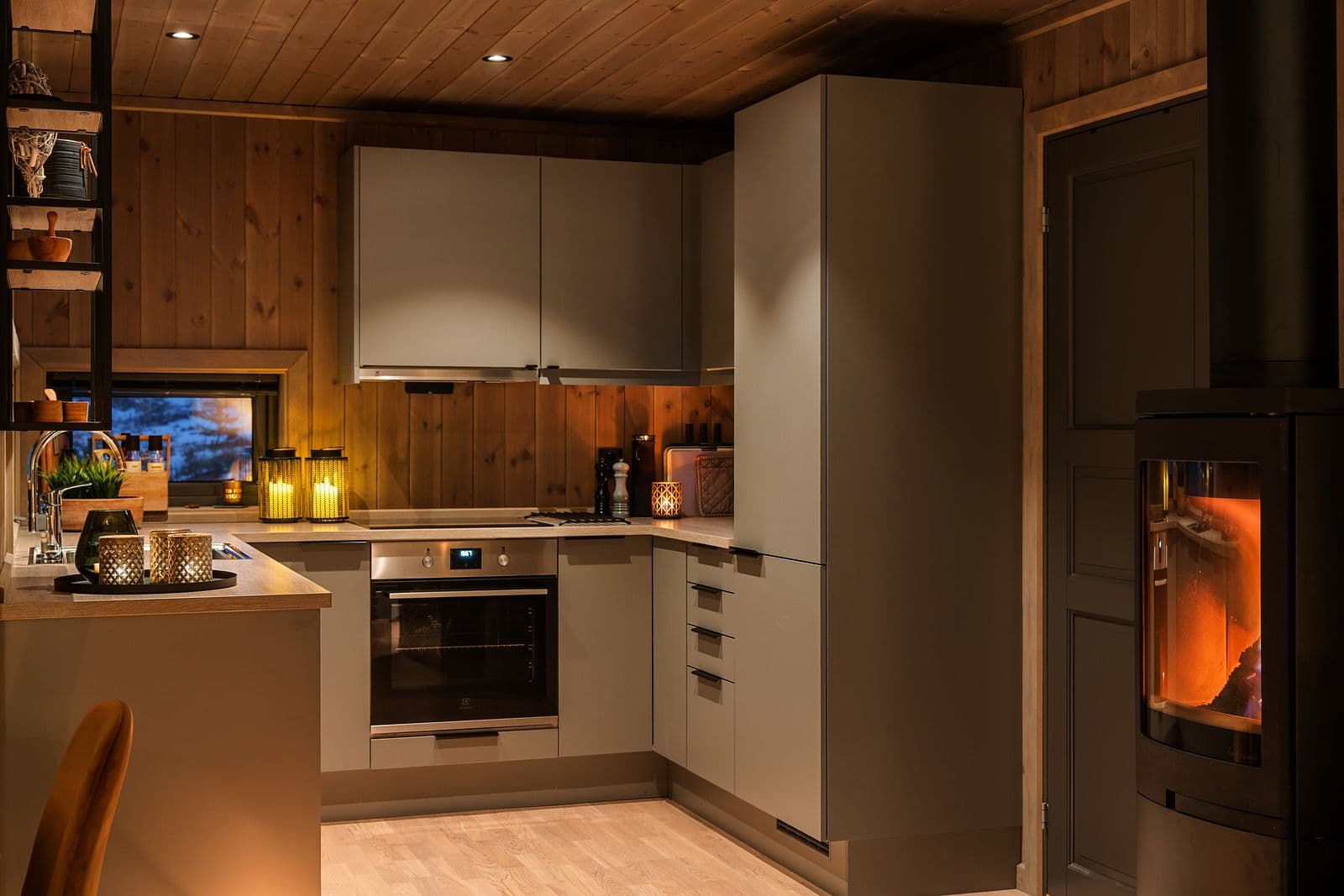 Midt i rommet står en stilfull Nordpeis peisovn, som ikke bare bidrar til god varme, men også fungerer som et naturlig blikkfang som samler hele rommet.