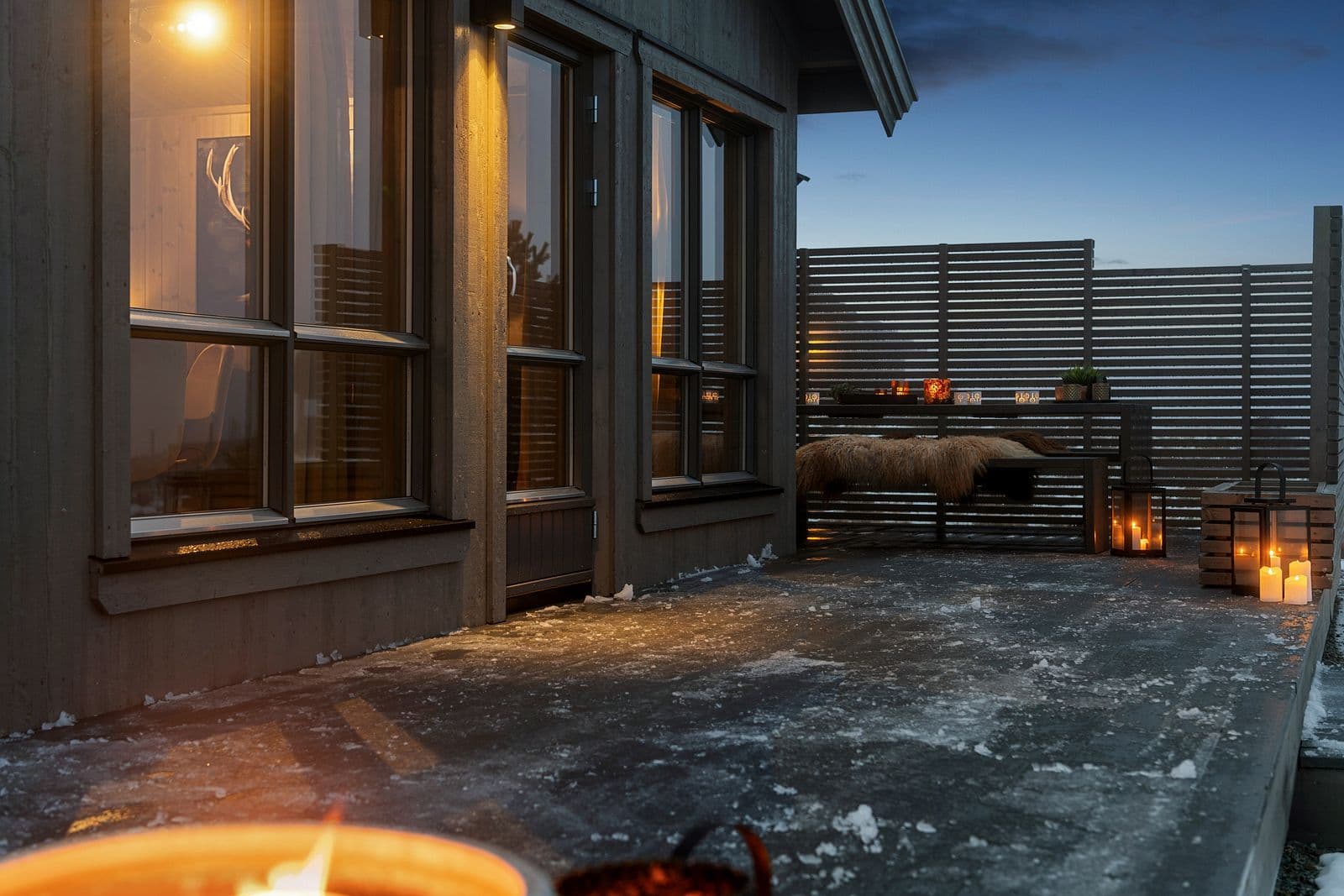 Hytta byr på en generøs terrasse som rammer inn uteområdet og gir rikelig med plass til både avslapning og sosiale stunder. De stilrene spileveggene skaper en lun og skjermet atmosfære, slik at du kan nyte fjellufta uansett vær.