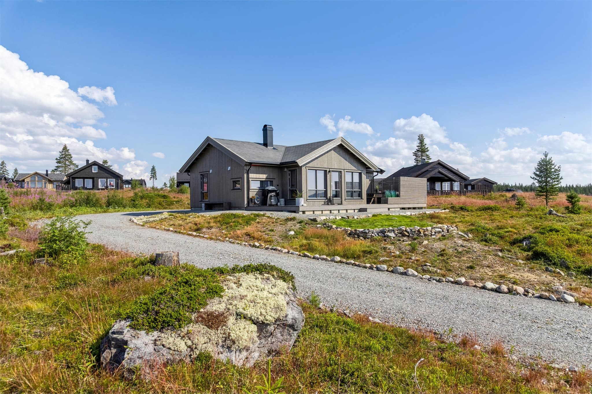 Hytta ligger på en svært romslig tomt på nærmere 2 mål, omgitt av ekte naturtomt med lyng, skogsbunn og vakre furutrær som rammer inn eiendommen. Den singelbelagte innkjøringen leder inn til en stor gårdsplass med god plass til flere biler.