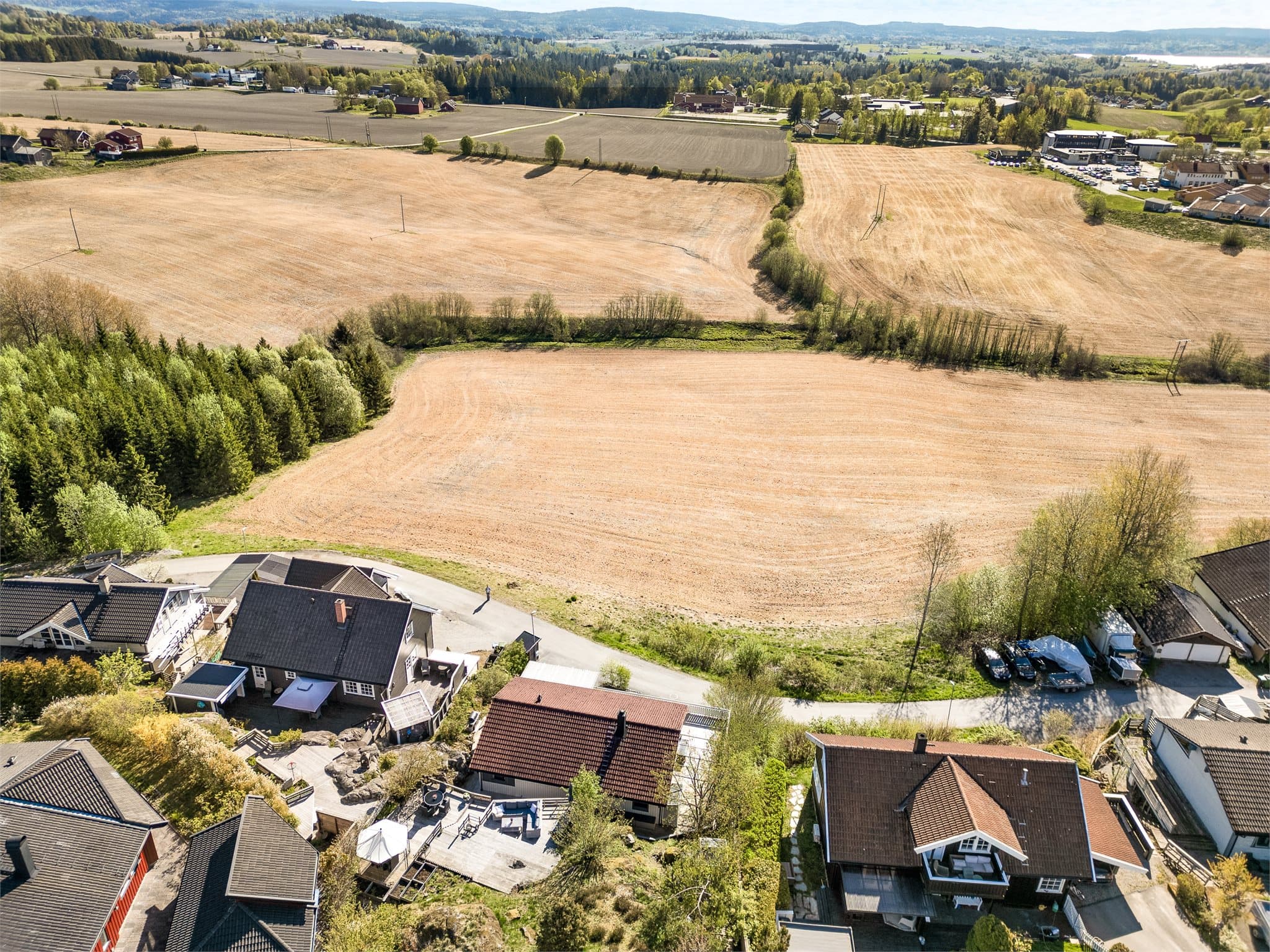 Fra droneperspektivet kommer eiendommens unike beliggenhet virkelig til sin rett – vakkert plassert i rolige omgivelser med vidstrakt utsyn over åpne åkre og det naturskjønne landskapet rundt Kirkebygda.