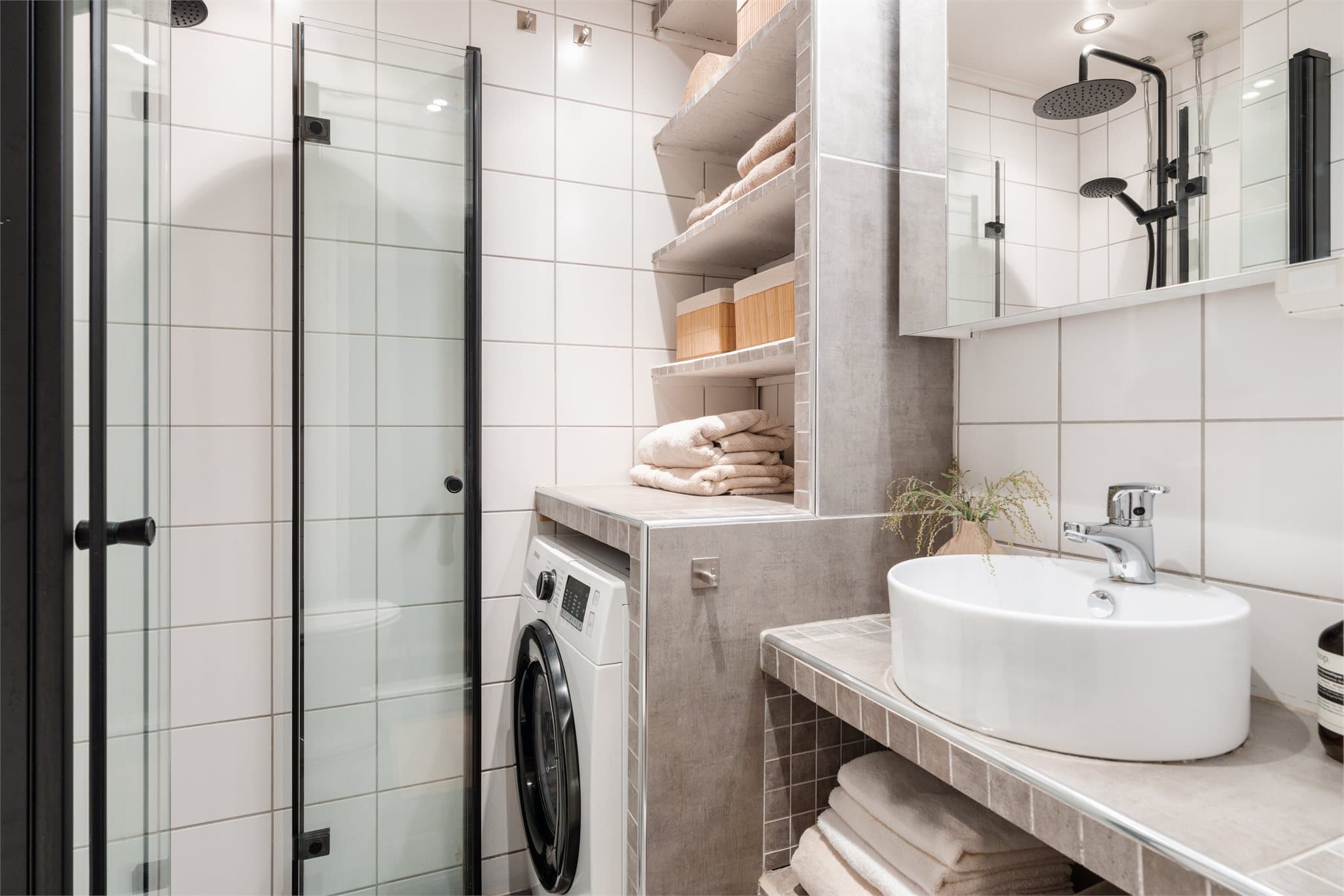 Leiligheten har et stilrent bad med fliser på gulv og vegger. Badet har varmekabler og opplegg for vaskemaskin.