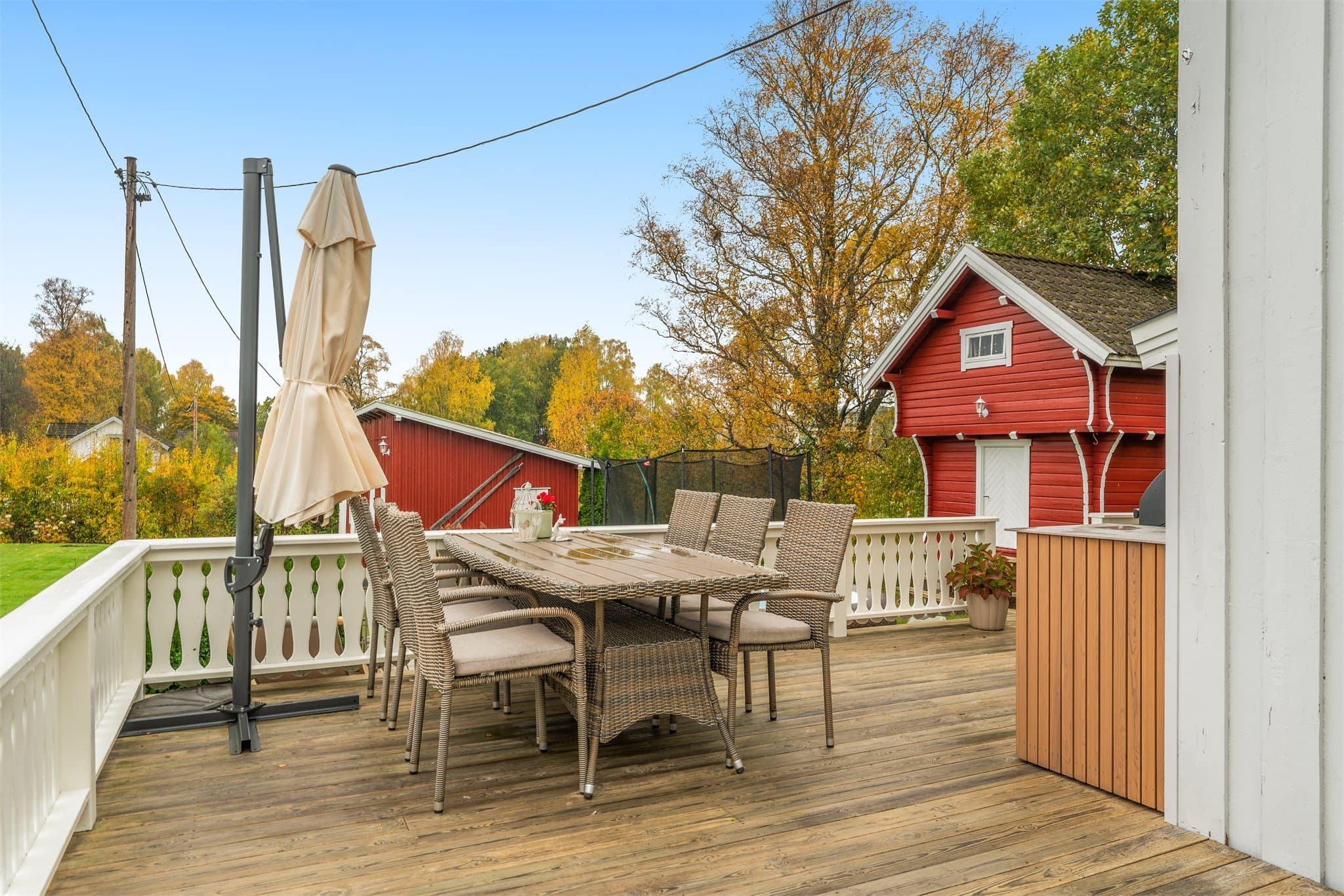 Terrasse med spiseplass og hvitmalt trerekkverk.