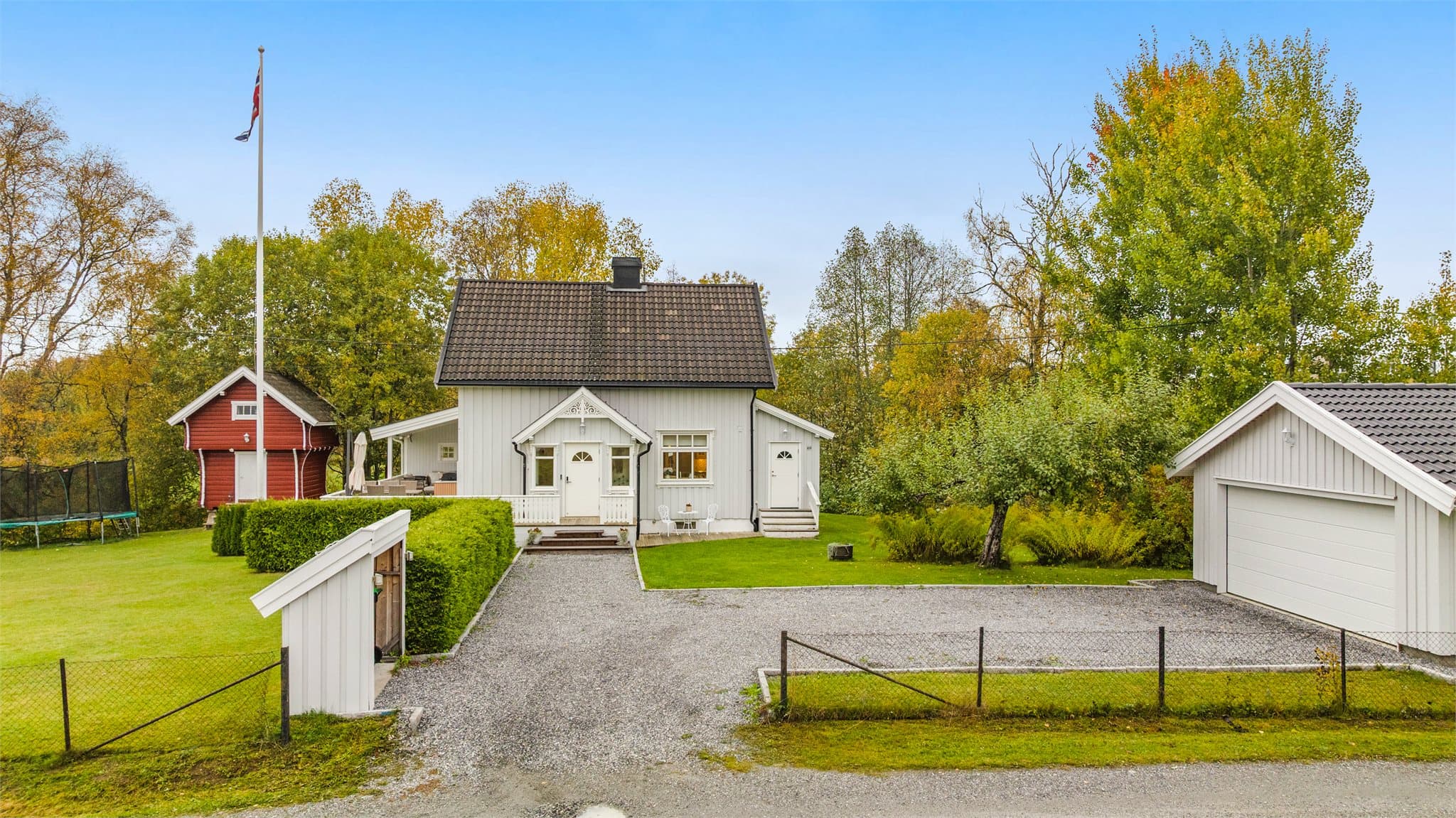 Bygningsmassen er samlet rundt det gruslagte tunet og den frodige hagen.
