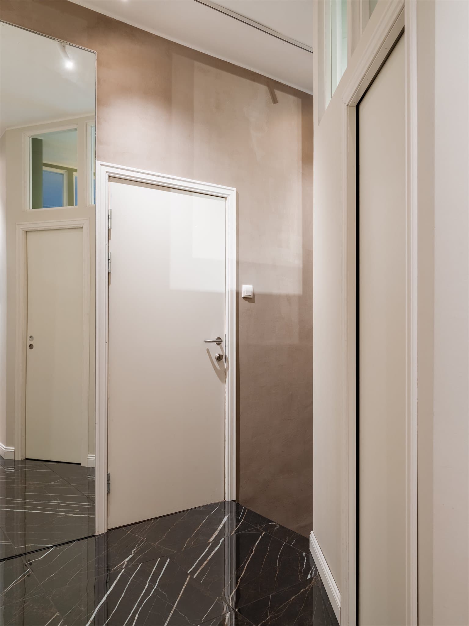 De mørke, marmormønstrede flisene skaper en elegant overgang mellom sonene.