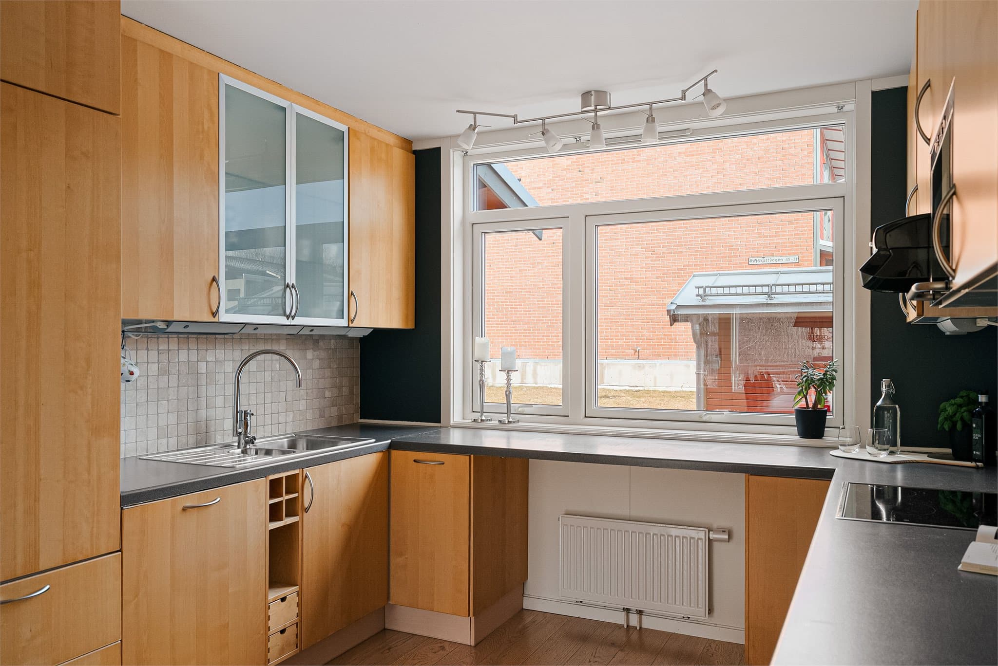 Praktisk kjøkkenløsning med stort vindu over benk som gir godt med dagslys.