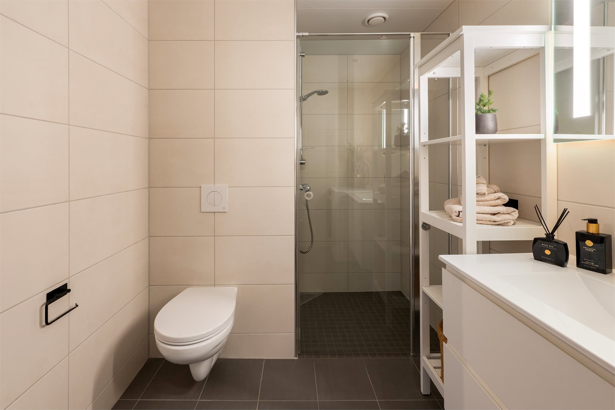 Rommet har innredning med nedfelt servant, veggmontert toalett, dusjhjørne og opplegg for vaskemaskin.