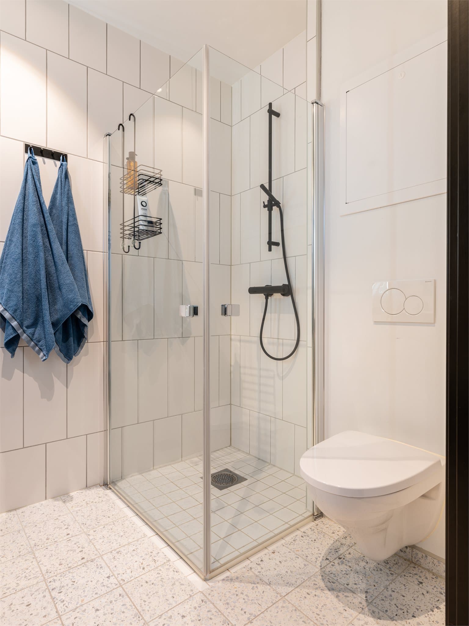 Dusjen er plassert på gulvet bak innfellbare dører i herdet glass.