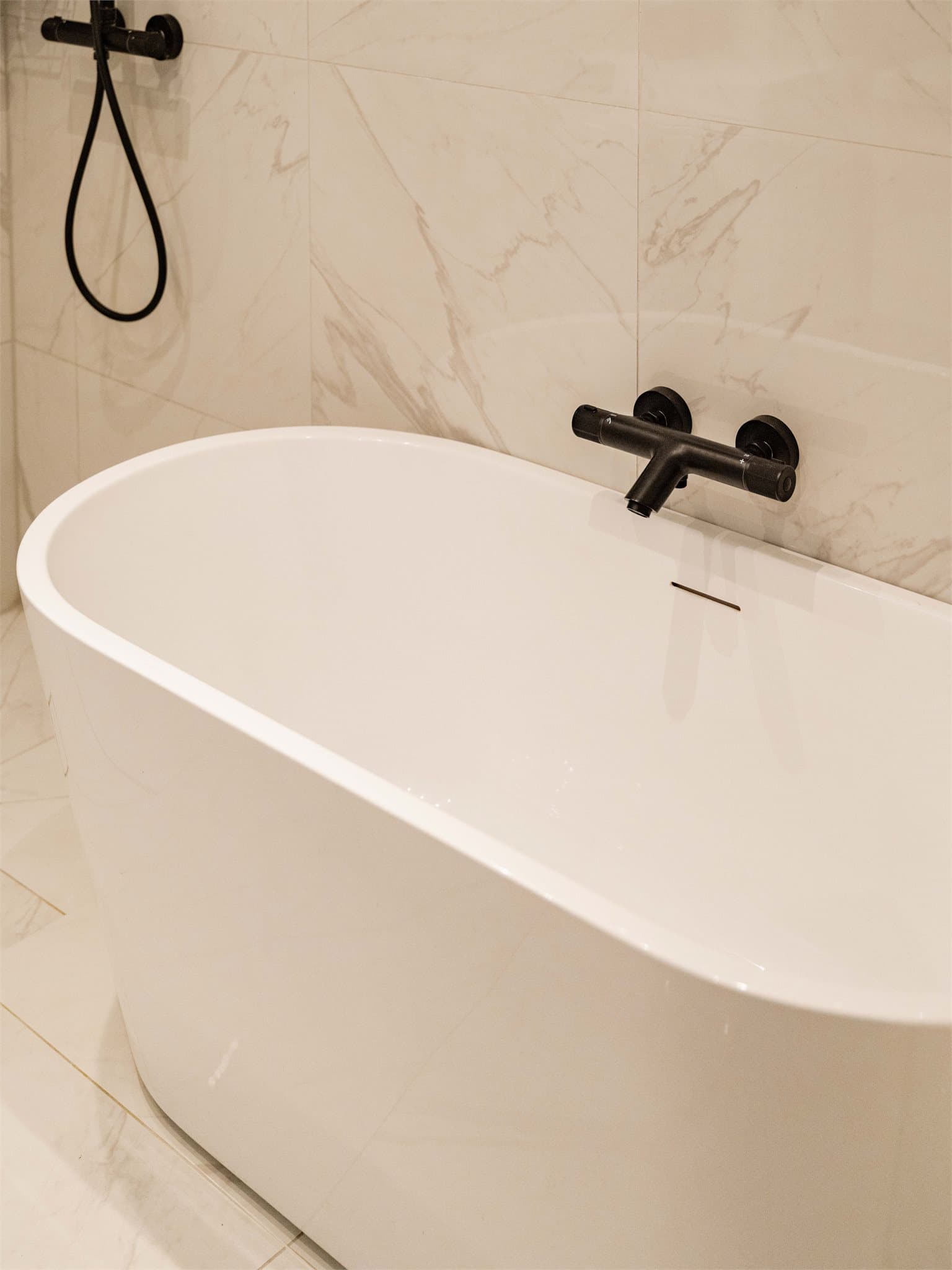 Innredningen består av badekar, vegghengt toalett og en moderne servant med ett-greps armatur, som sammen gir badet et tidløst og funksjonelt preg.