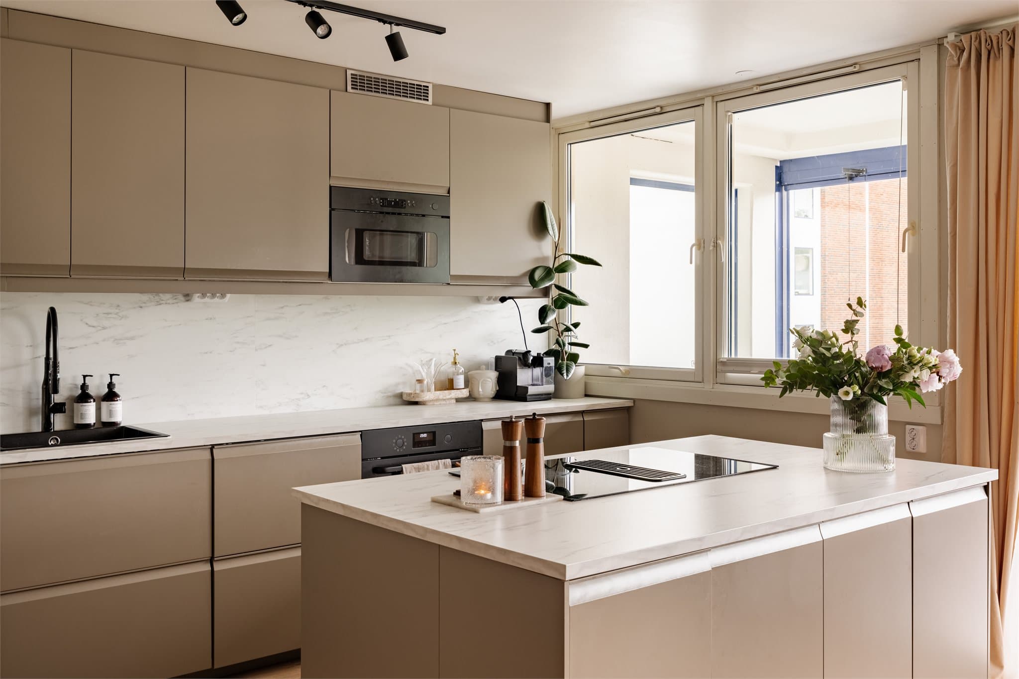Kjøkkenet fra 2024 fremstår stilrent og tidsriktig med elegante, beige slette fronter fra IKEA som harmonerer flott med leilighetens moderne uttrykk.